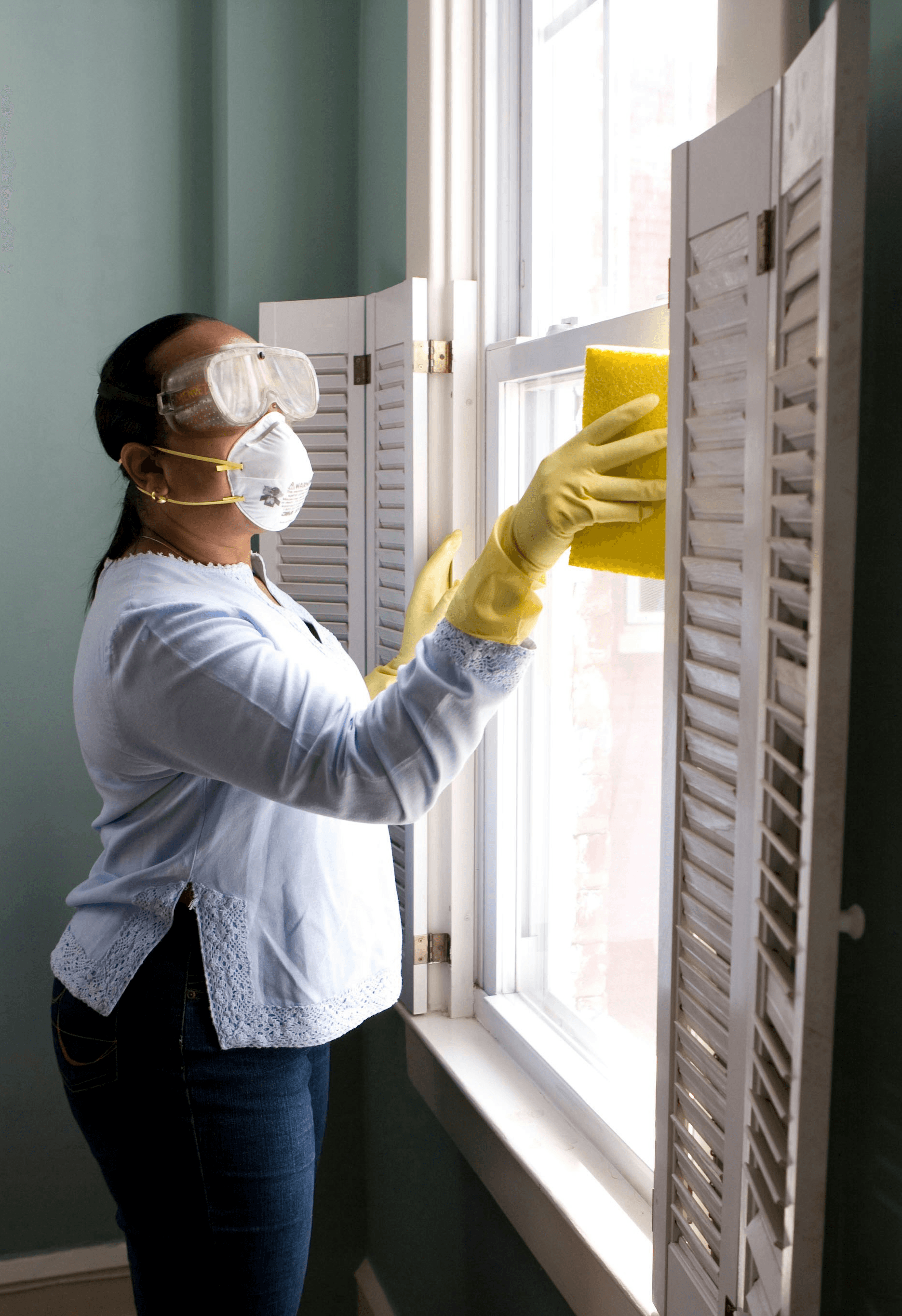 woman in white long sleeve shirt and blue denim jeans standing beside white wooden framed glass