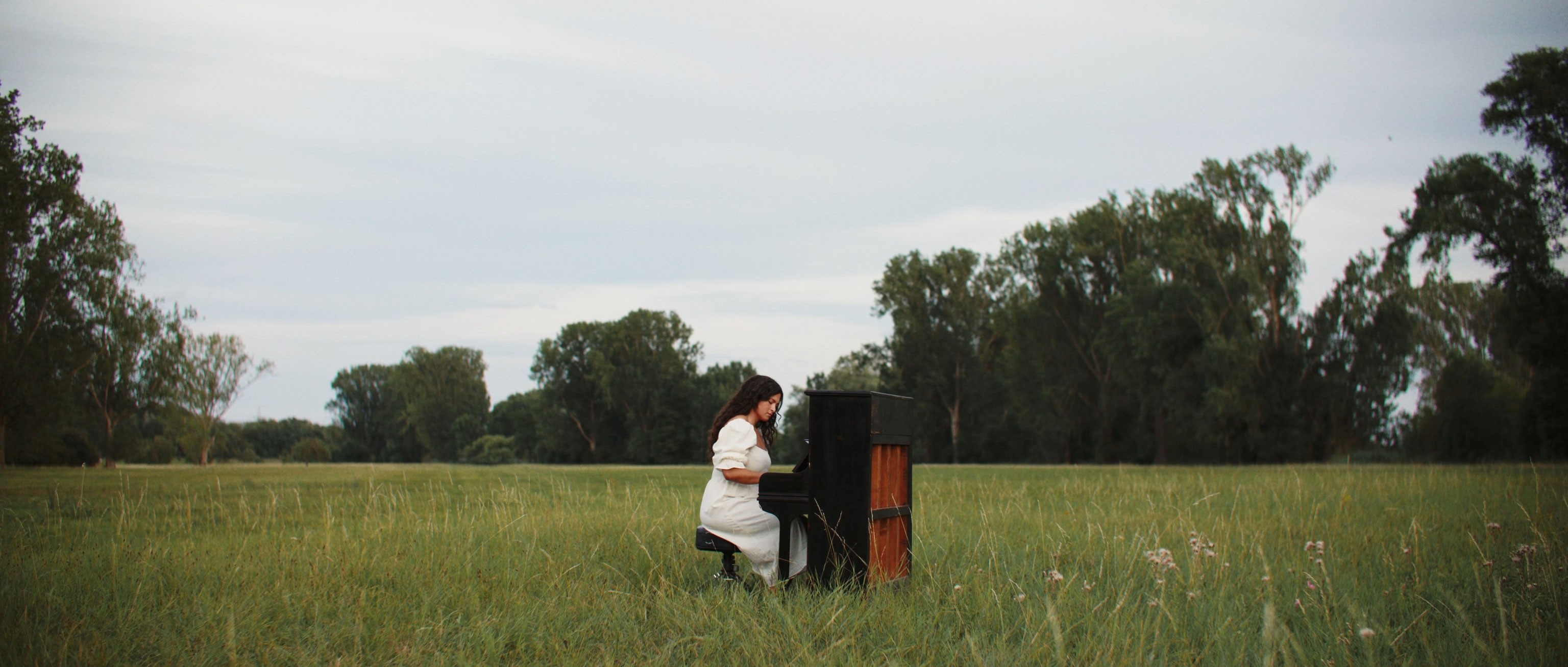 a woman sits in the natur at a piano