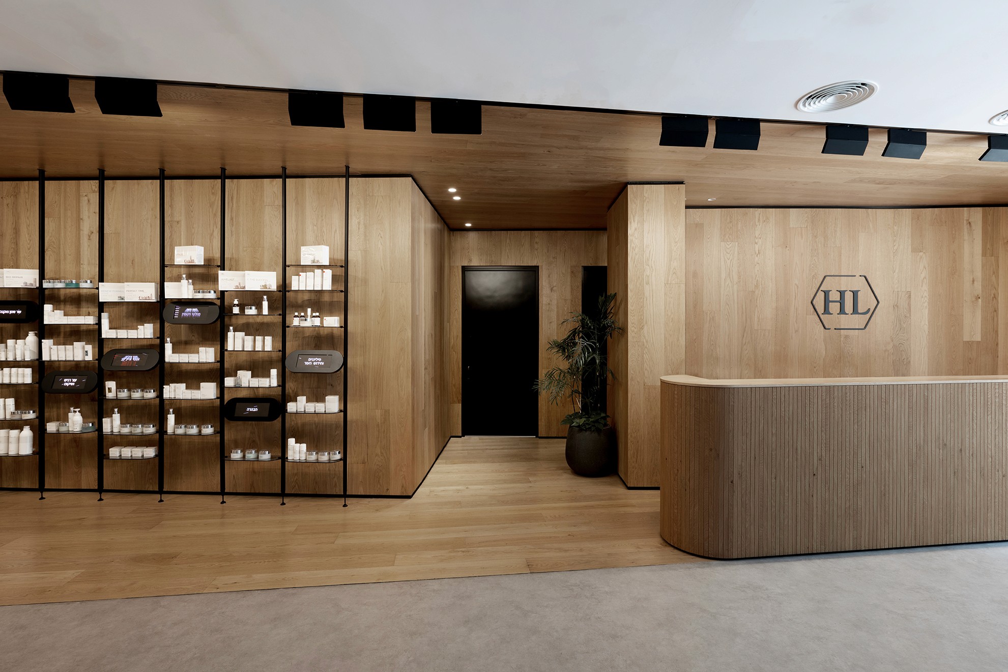 כניסה וקבלה: דלפק מחופה עץ אלון עם חריצים אנכיים (Vertical Slats) ולוגו החברה בחיתוך CNC, המייצרים מראה נקי ומקצועי.