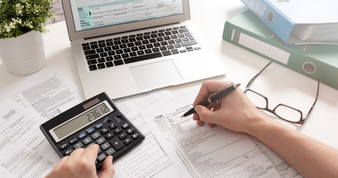 CPA working on tax documents with a calculator and laptop