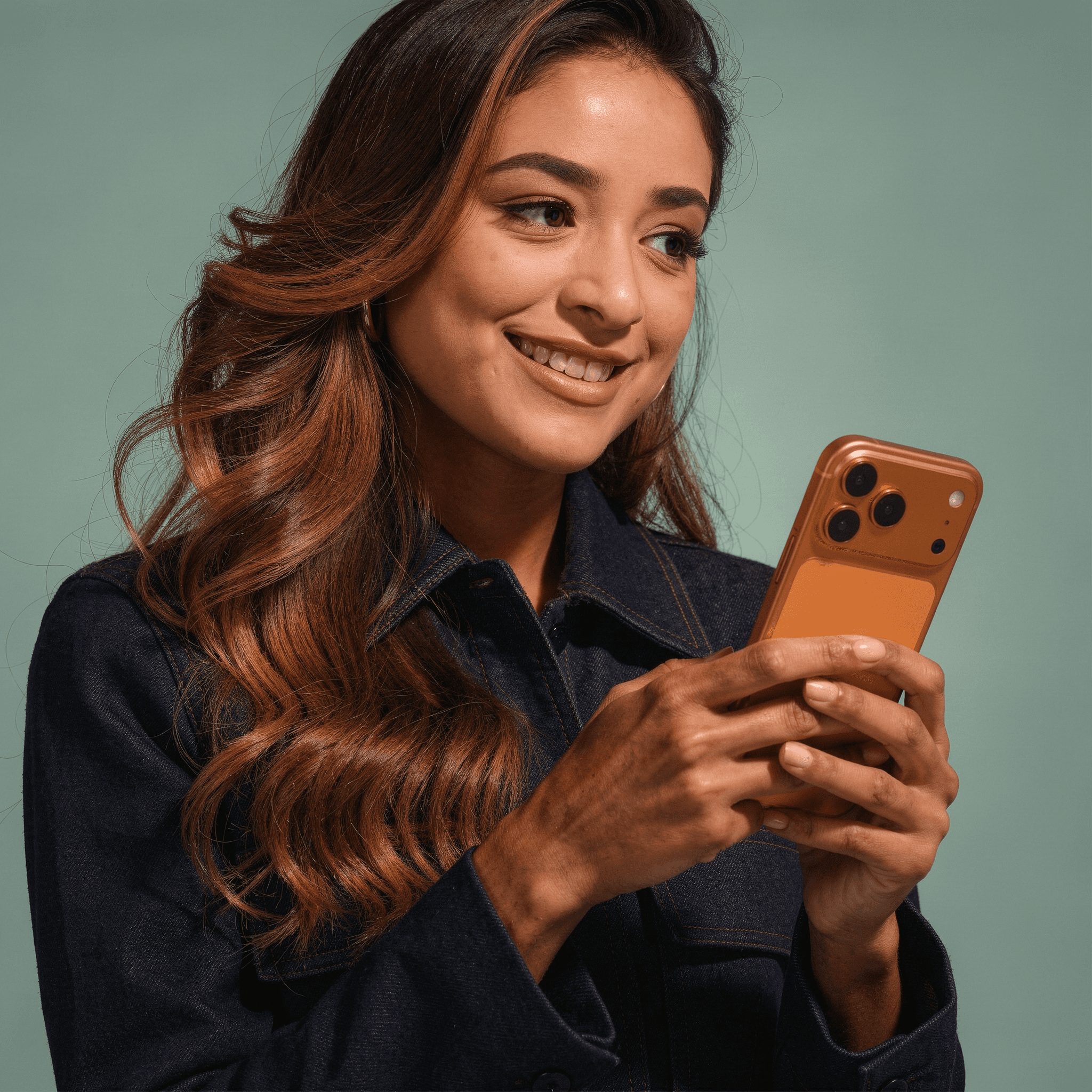 Woman smiling at orange smartphone.