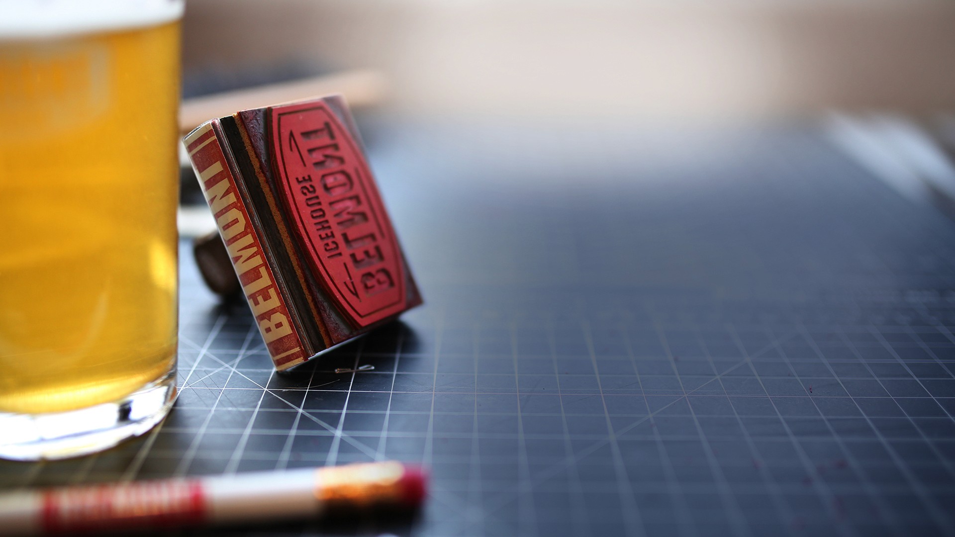 Belmont Stamp on work table with glass of beer