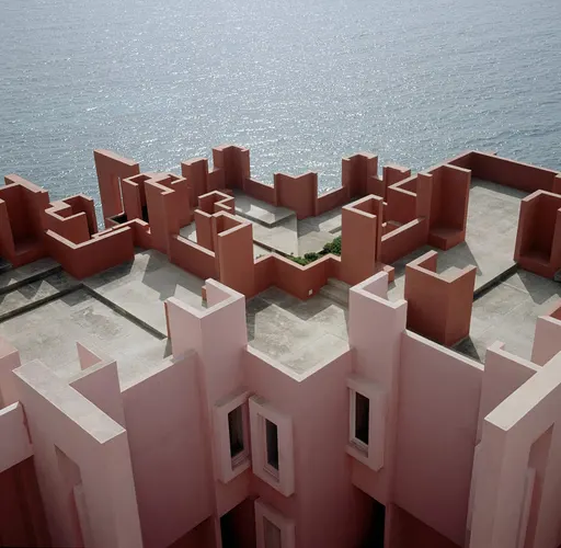 Geometric pink architectural structure by the sea with bold shapes and strong shadows.