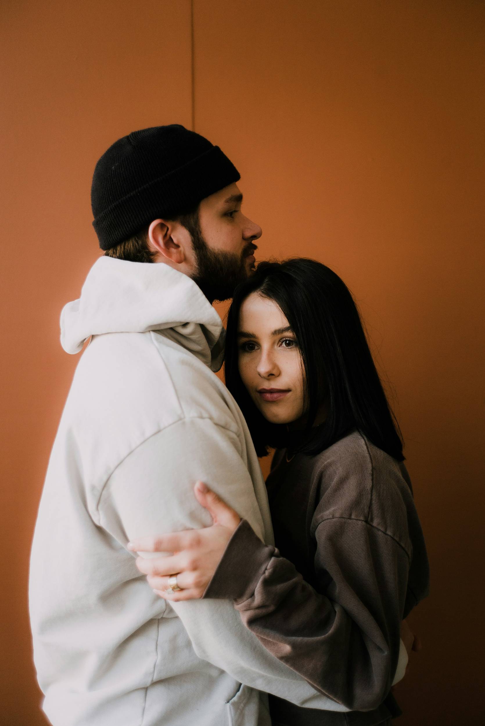 A couple embracing in front of an orange studio backdrop