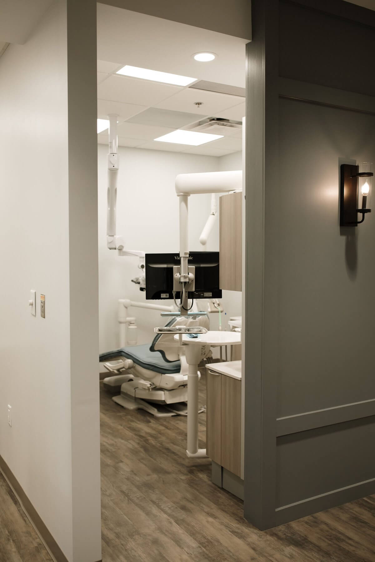 A modern, well-lit office space viewed through an open doorway, featuring a desk and chair.