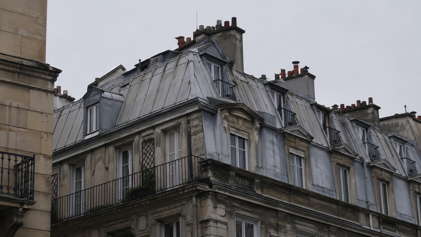 Toiture parisienne en secteur ancien Immeuble parisien à toiture à la Mansart, brisis en ardoise, terrassons en zinc et souches de cheminée