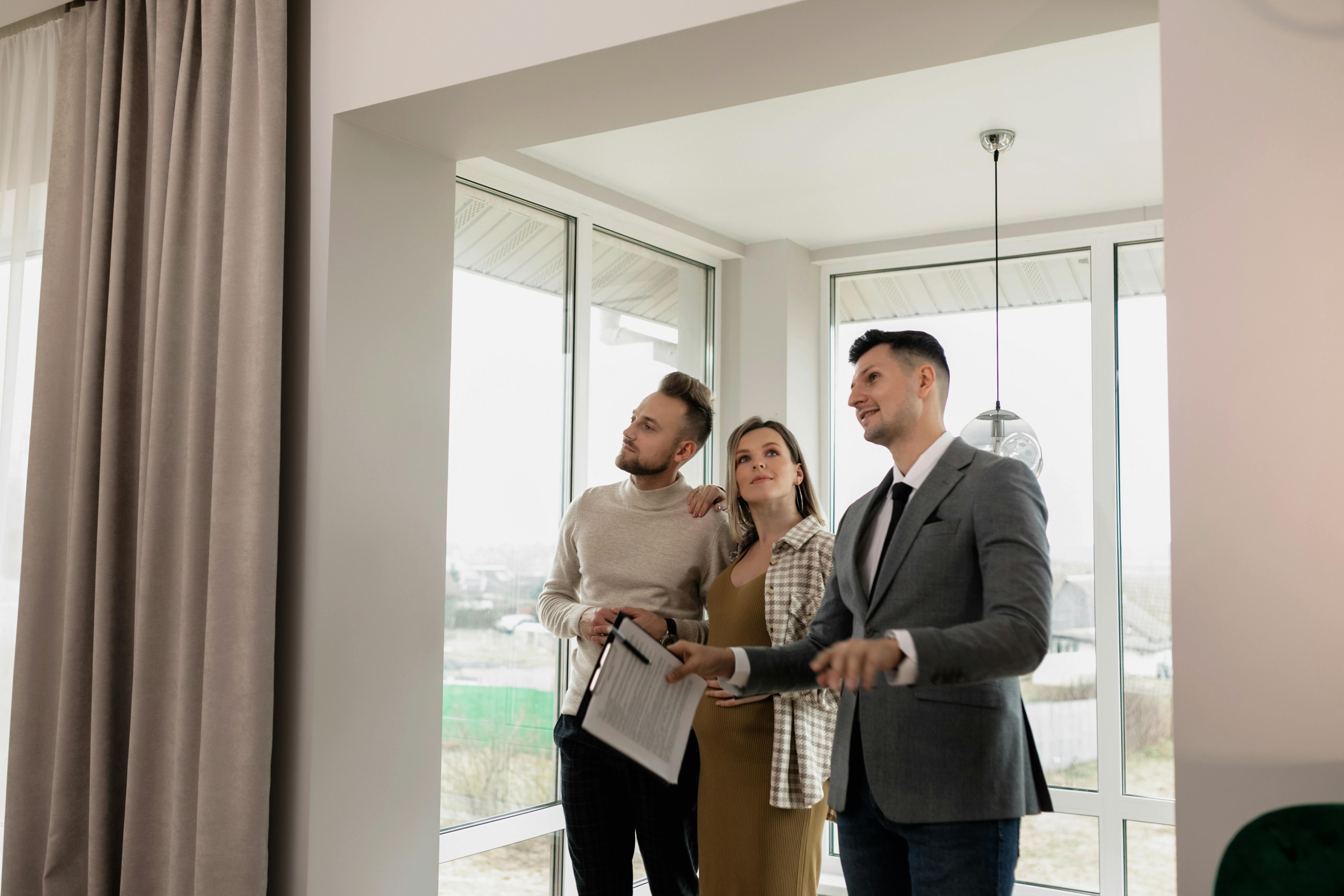 Three people standing together in a bright, modern interior, looking at a document and discussing.