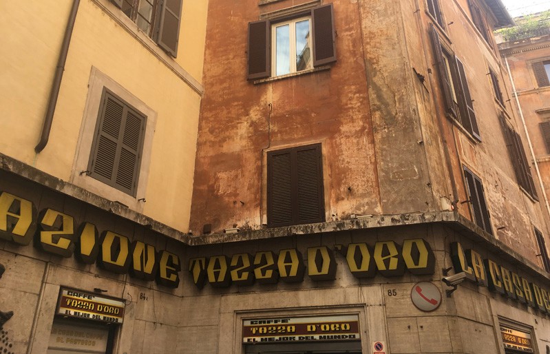 A photo of an old building with some shops at the bottom and some text over the entrances.