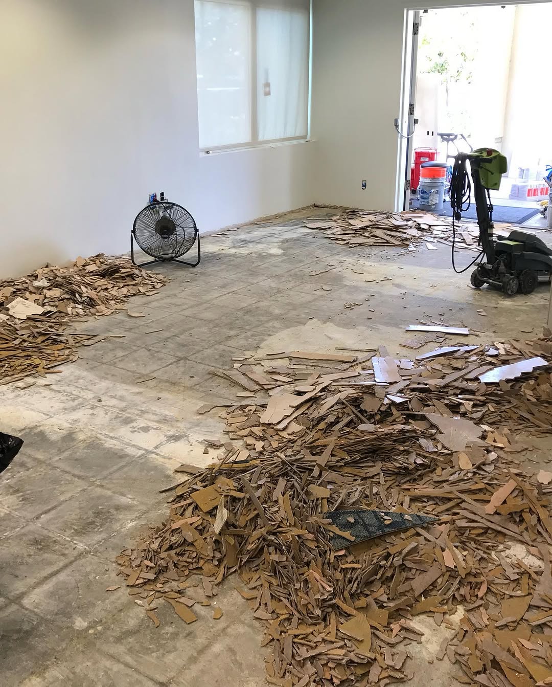Demolished flooring piled on the bare slab of a break room