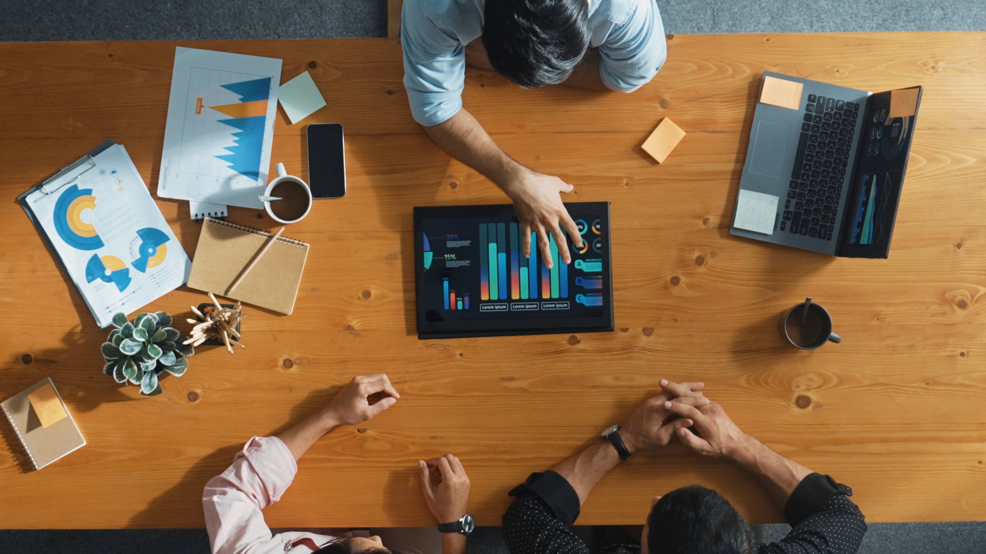 a group of people sitting around a table with laptops