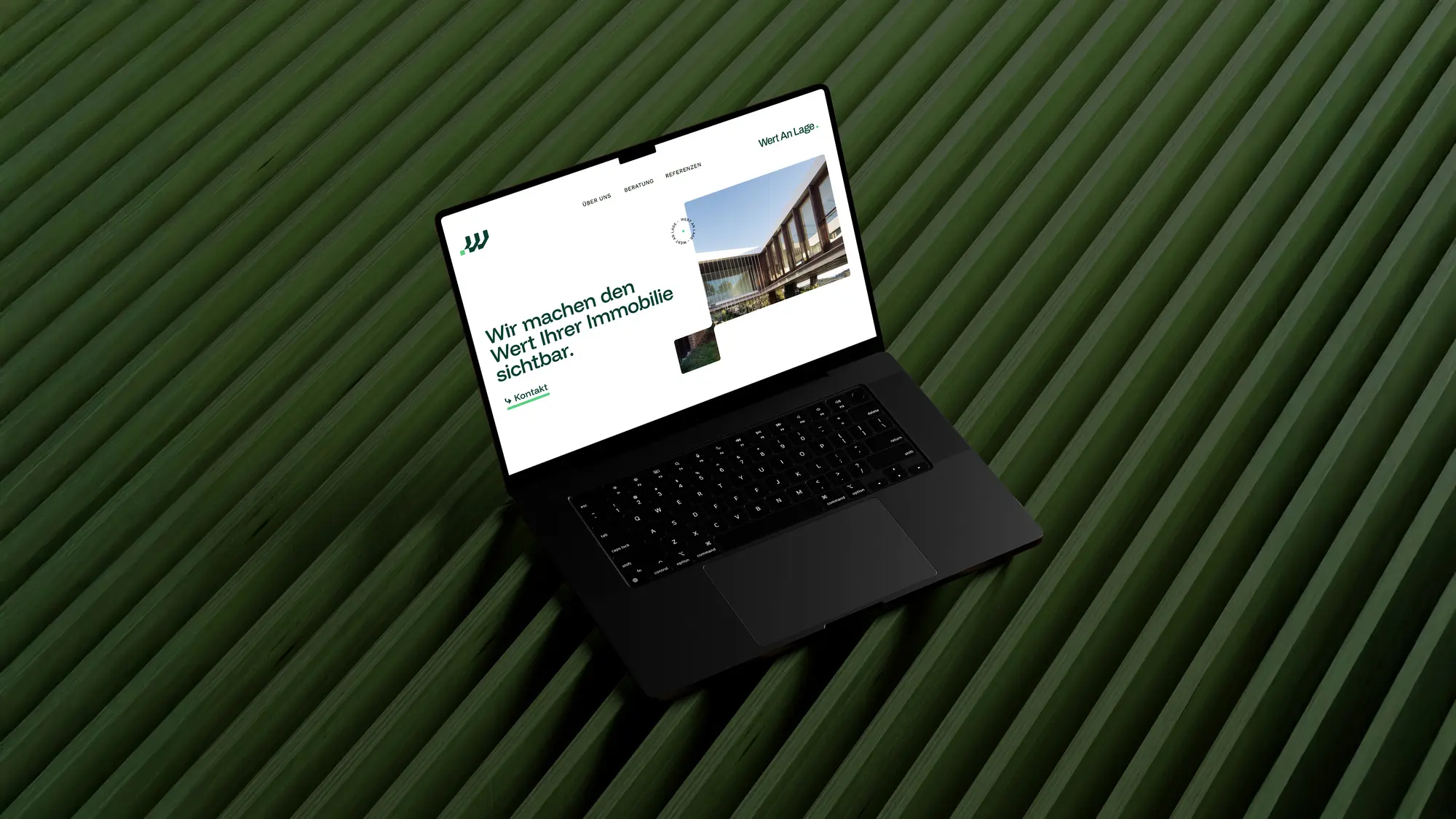 Ein Bild von einem schwarzen Macbook welches ein mögliches Websitelayout von Wert an Lage zeigt auf einem dunkelgrünen gerillten Hintergrund.