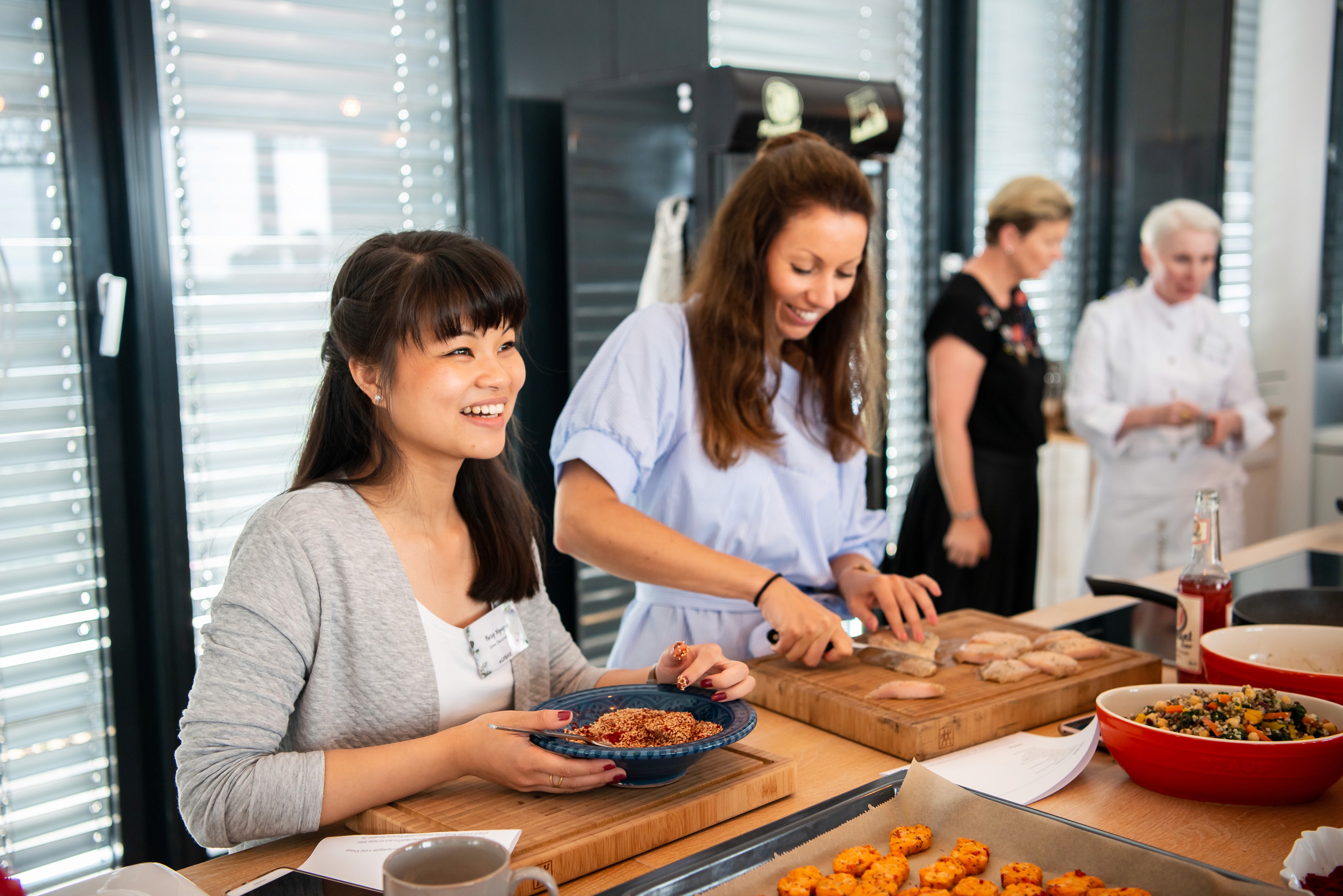 Zwei Frauen gestalten Weihnachtsbaumdekoration bei einem DIY-Workshop an einem Holztisch im geschmückten Zelt. 