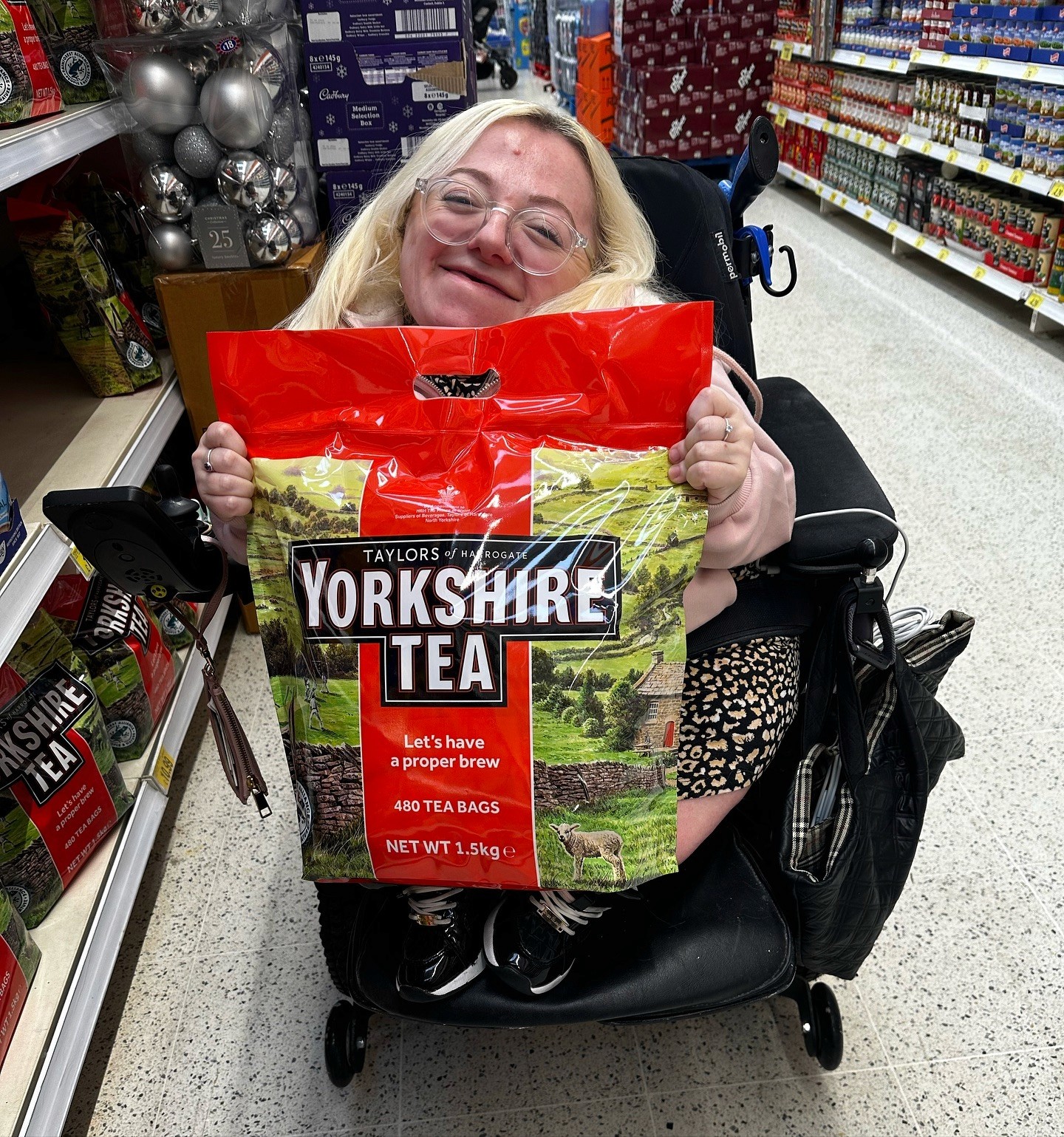 Gem in her wheelchair holding a HUGE bag of Yorkshire Tea
