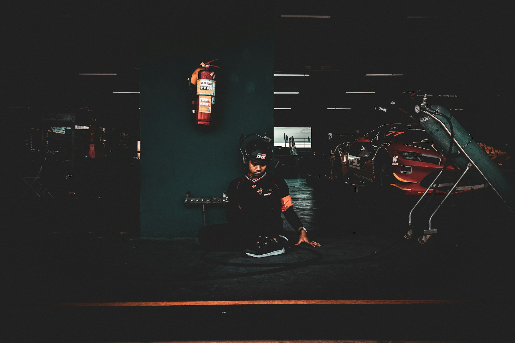 Person working beside race cars in a dark garage