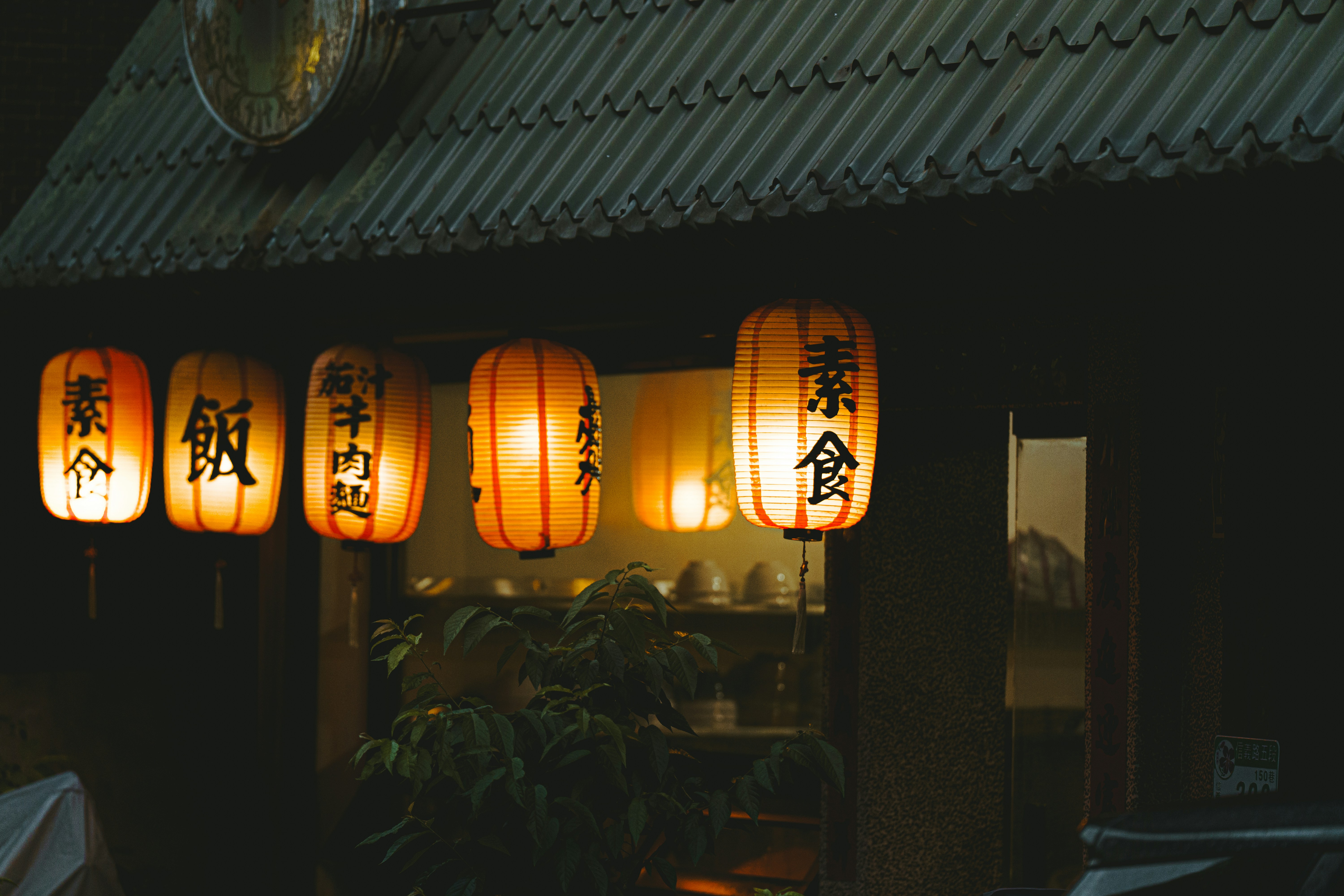 Japanese lanterns hang outside a dark building at dusk building.