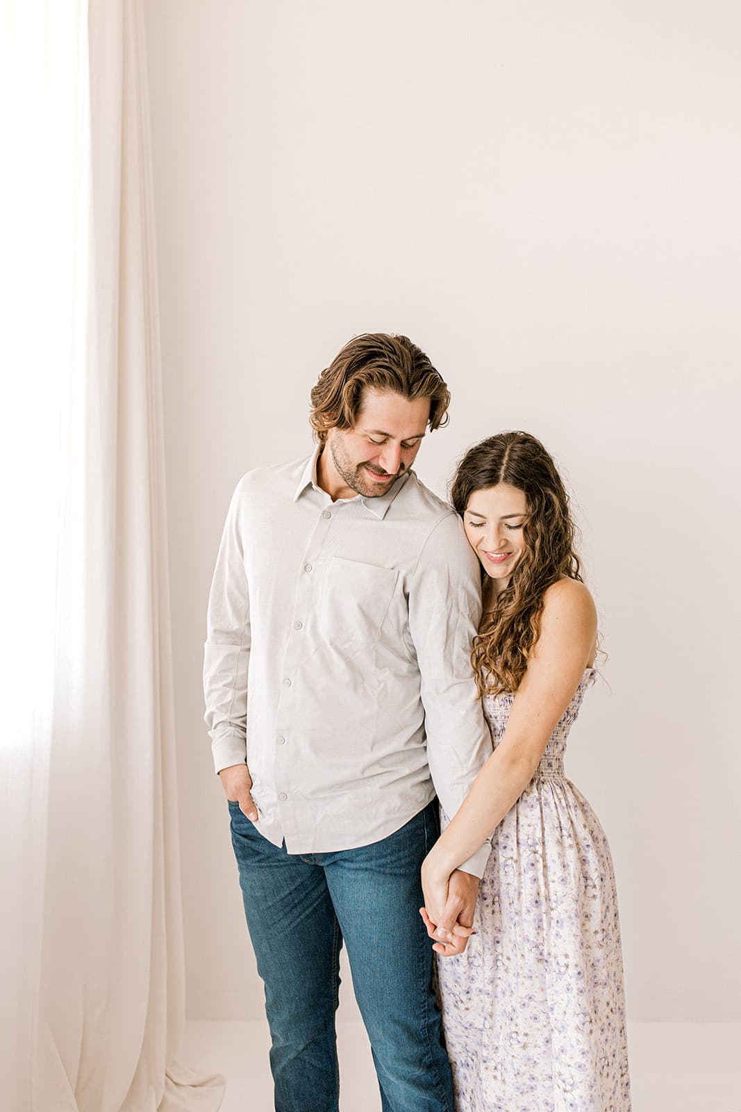 A couple standing close, holding hands and smiling, inside Revelator Studio in Shreveport.