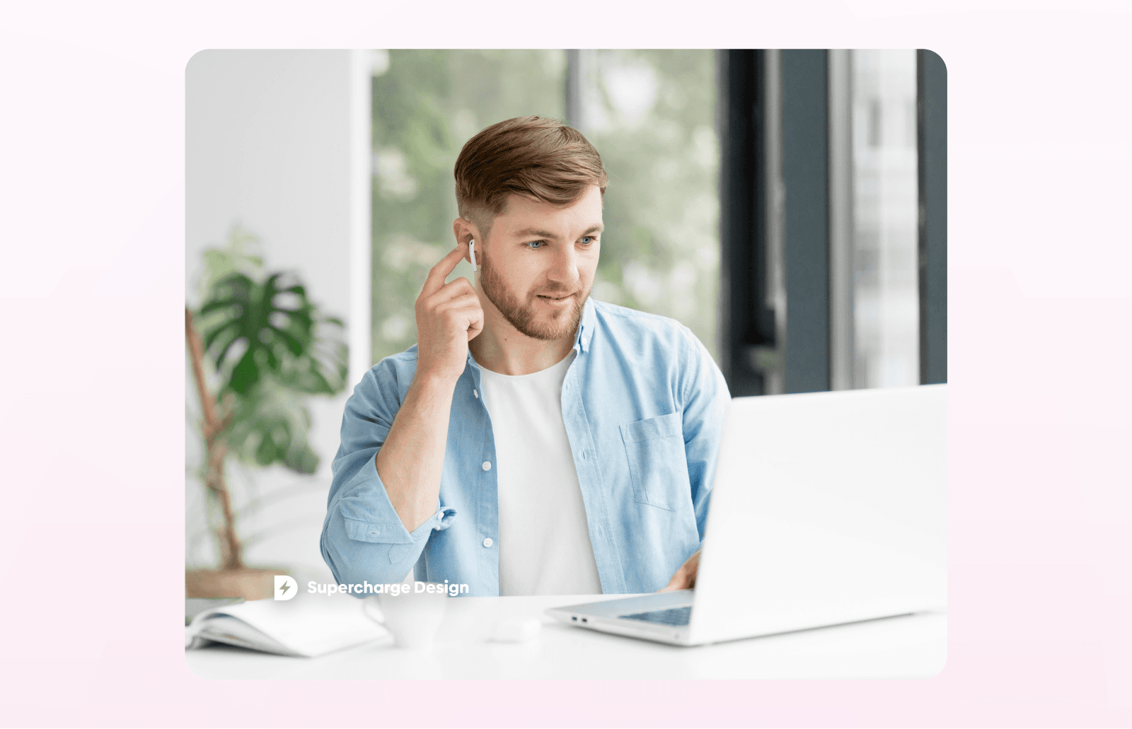 Person wearing wireless earbuds and working on a laptop in a bright home office, appearing to listen attentively during an online meeting or learning session. Supercharge Design branding is visible in the corner.