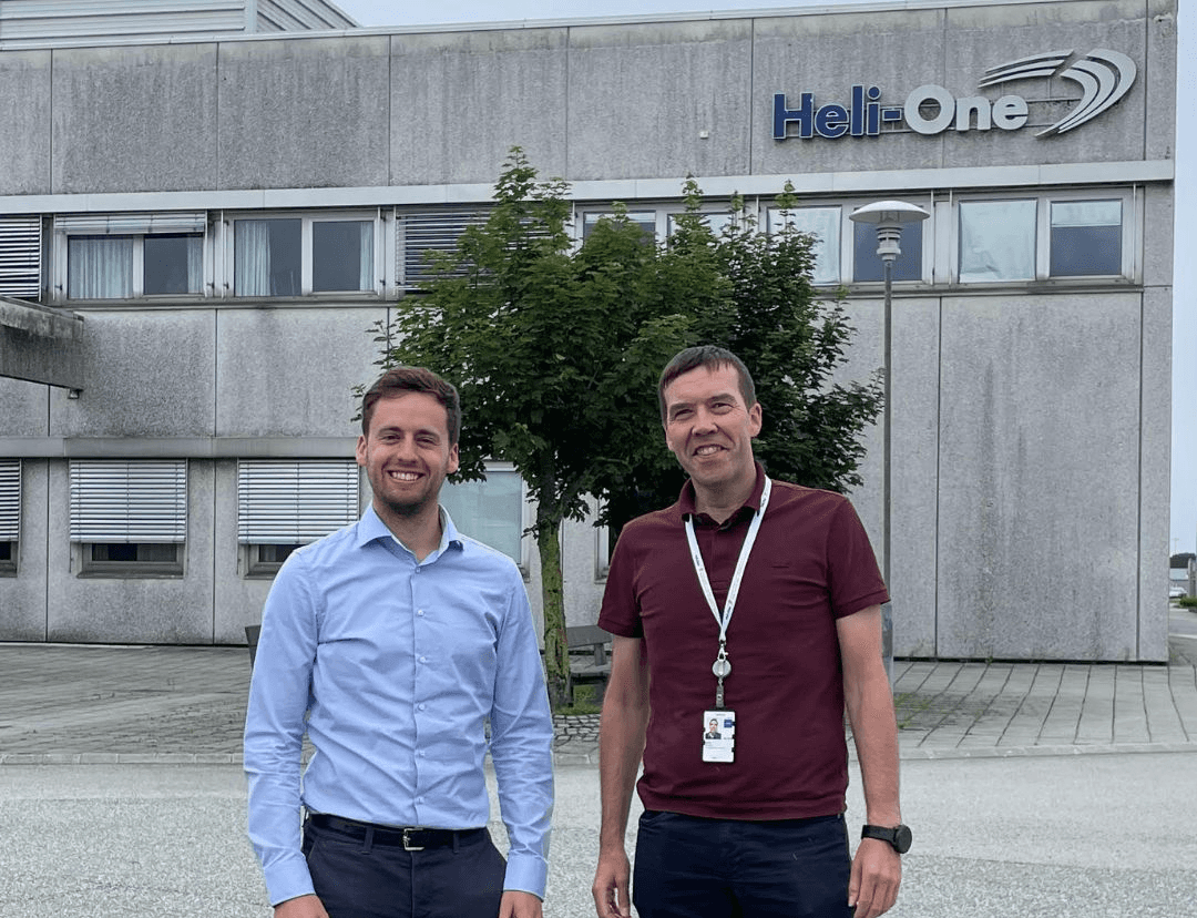 Two men standing in front of the Heli-One building, looking at the camera.