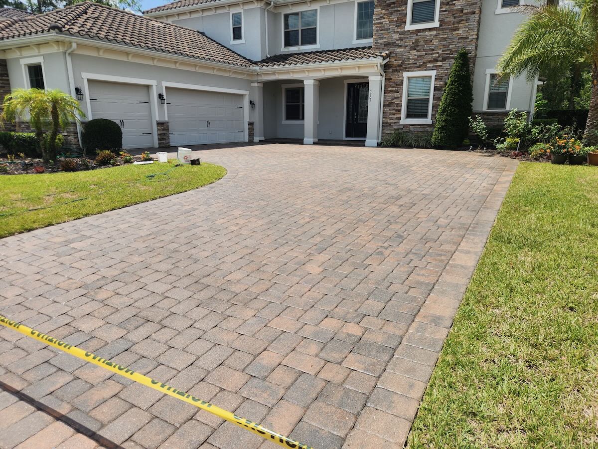 Freshly sealed paver driveway drying behind caution tape in Central Florida
