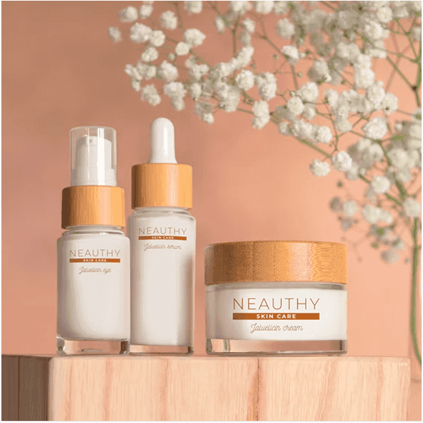 Three minimalist skincare bottles with bamboo caps displayed on a wooden block against a warm beige background.