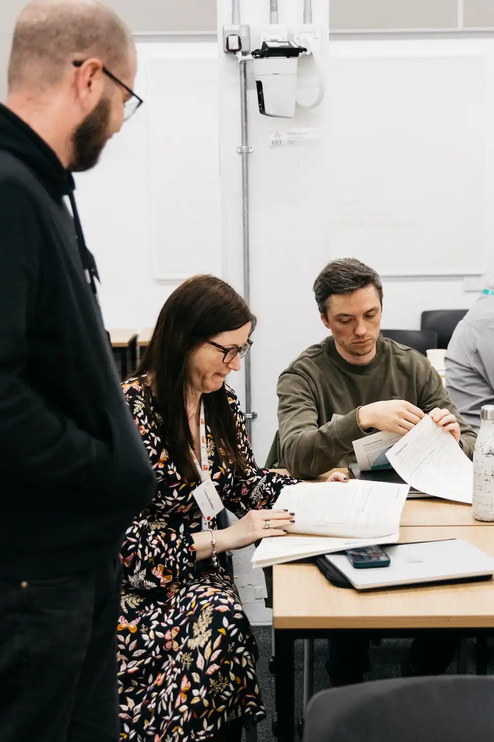 People standing at a table with papers and cups.