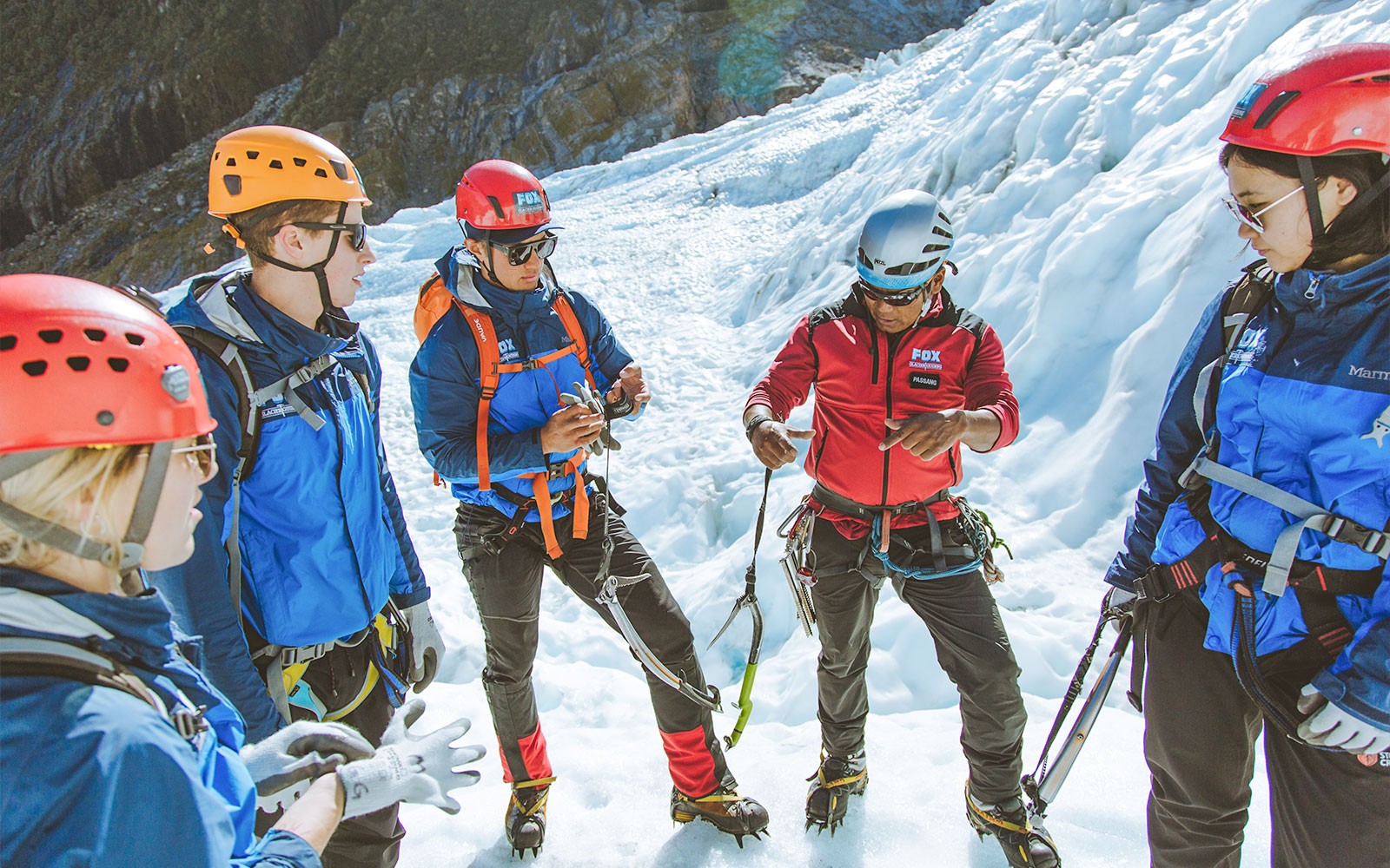 Grupo preparándose para la caminata en helicóptero en Fox Glacier con guía en terreno nevado.