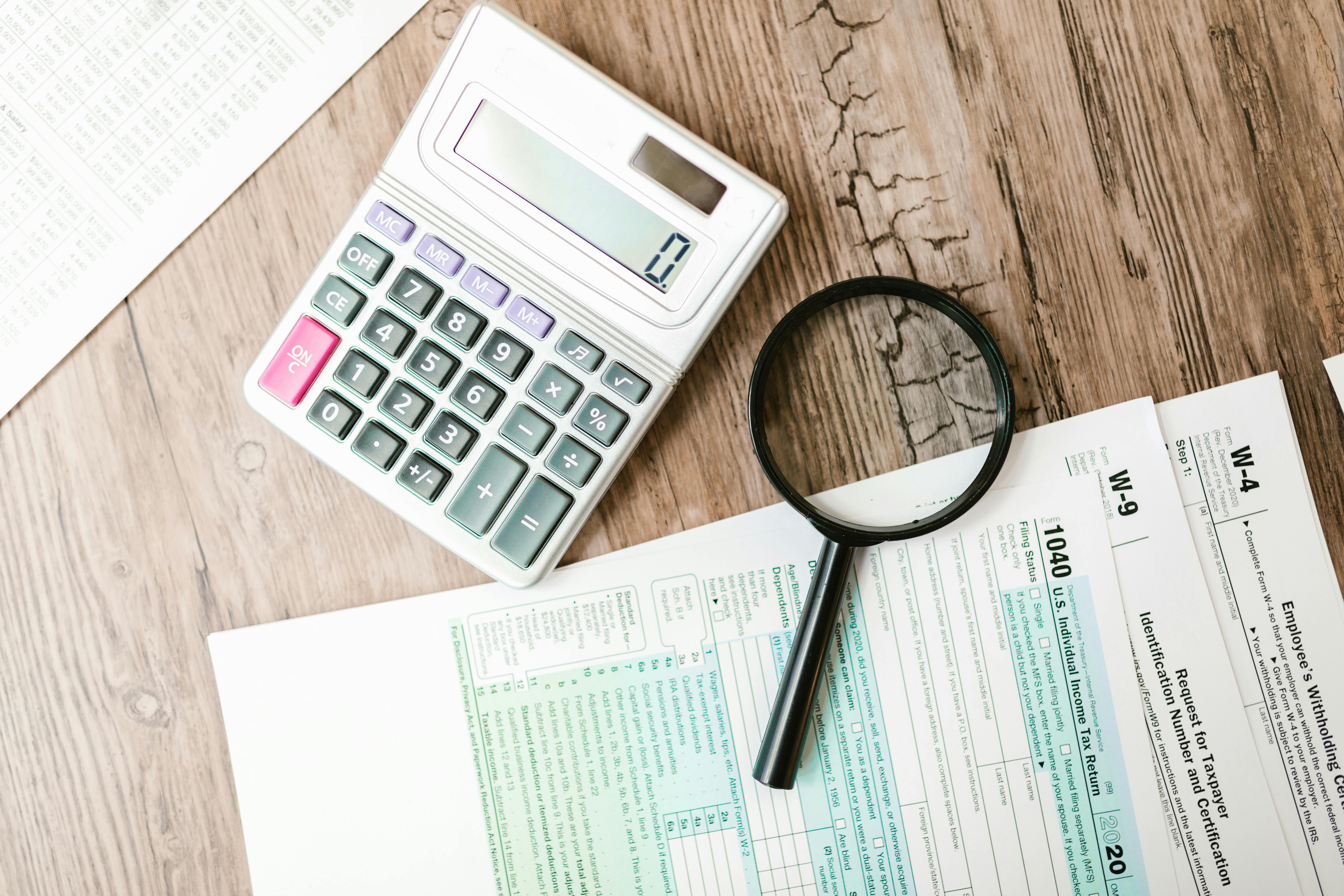 Tax forms with calculator and magnifying glass on wooden desk, analyzing Romanian fiscal residency rules under ANAF for foreigners
