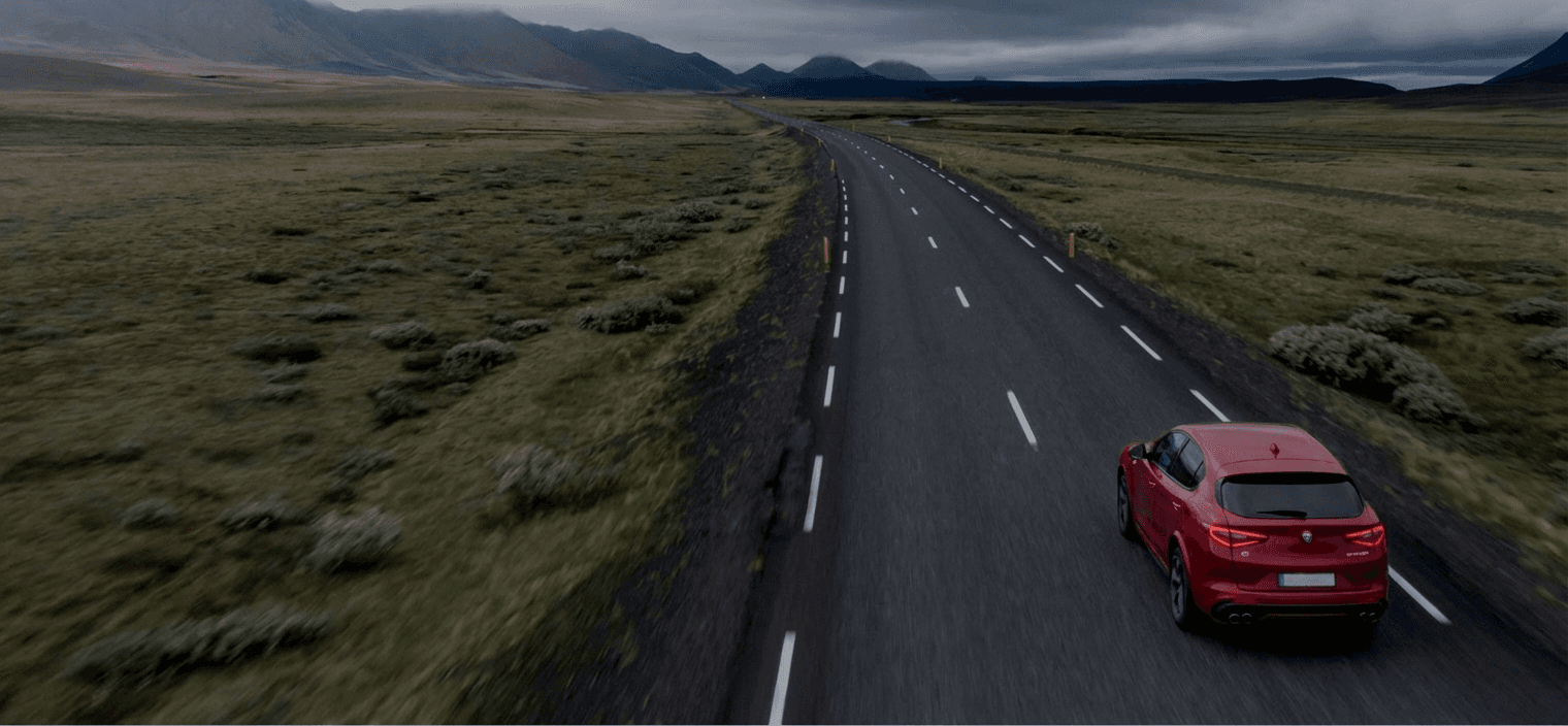 car driving a long road in the green forest