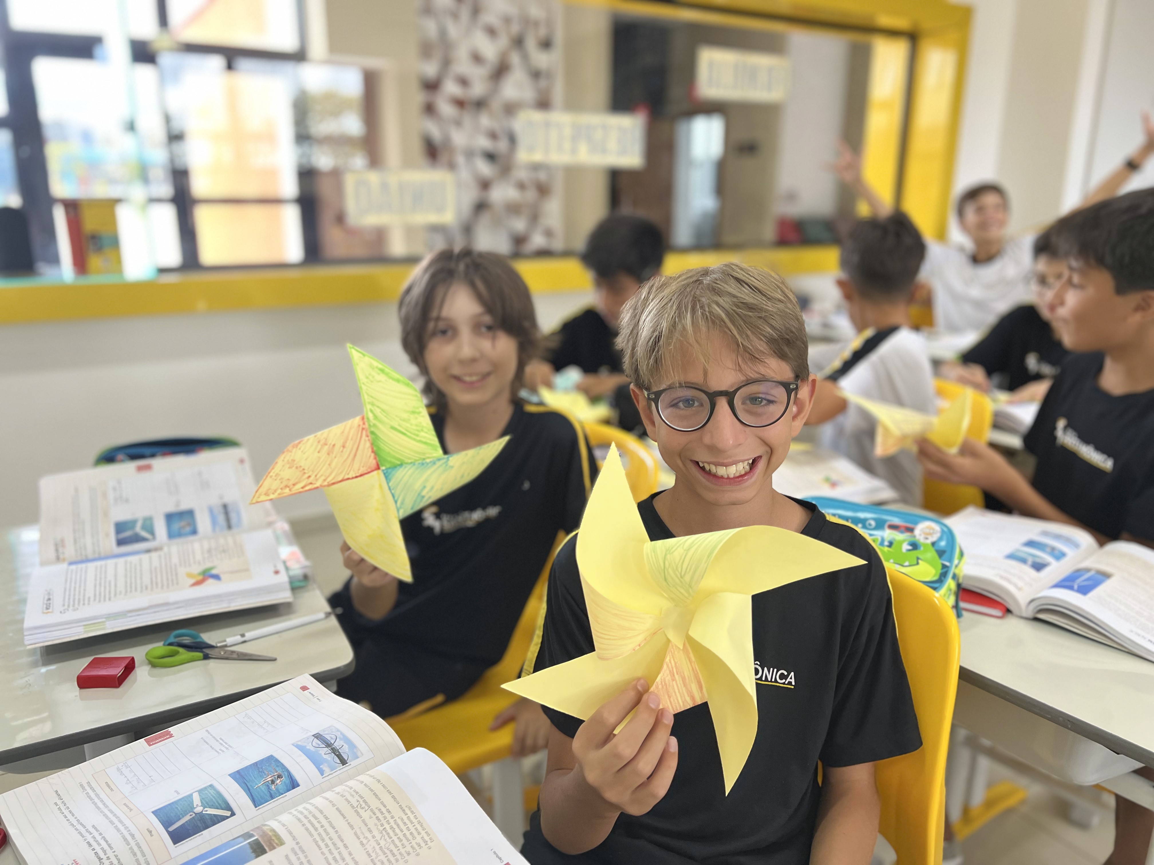 Alunos da Escola Santa Mônica constroem cata-vento em atividade prática para explorar simetria de rotação e movimento rotacional na aula de matemática.