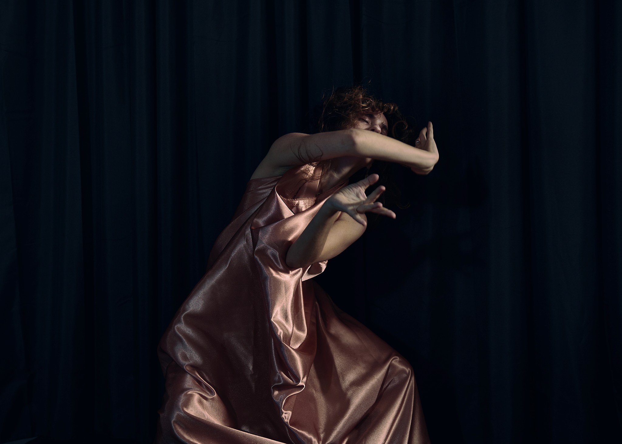Dancer captured mid performance with artistic and expressive movements against a dark background.