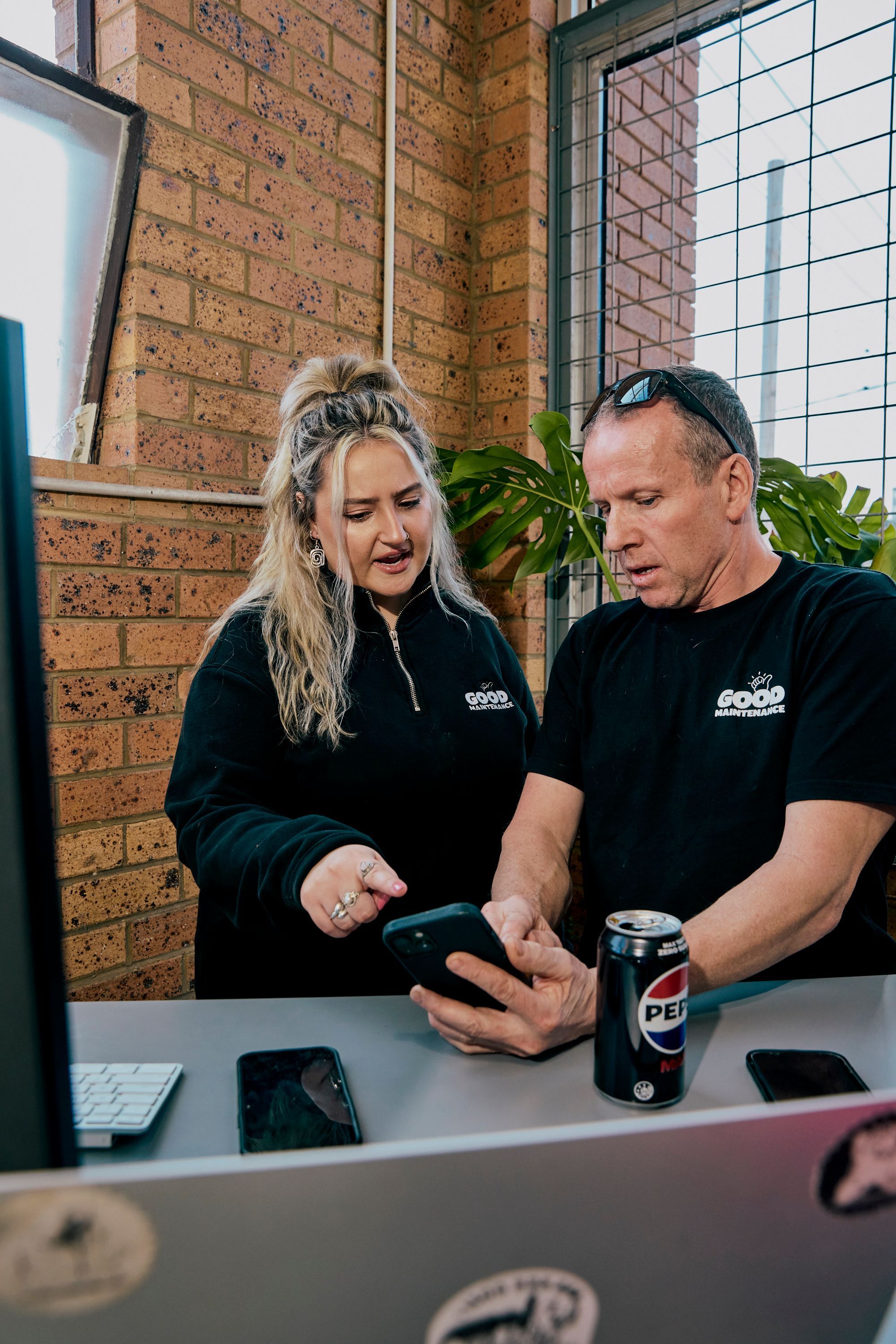 Good Maintenance team members reviewing work on a smartphone in the office.