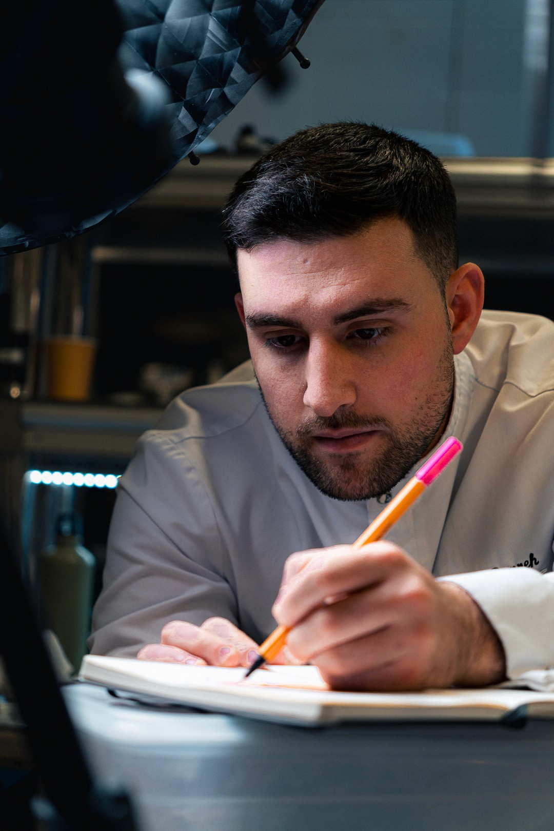Gros plan sur le chef Jonathan Bonneh dessinant un dessert dans son carnet.