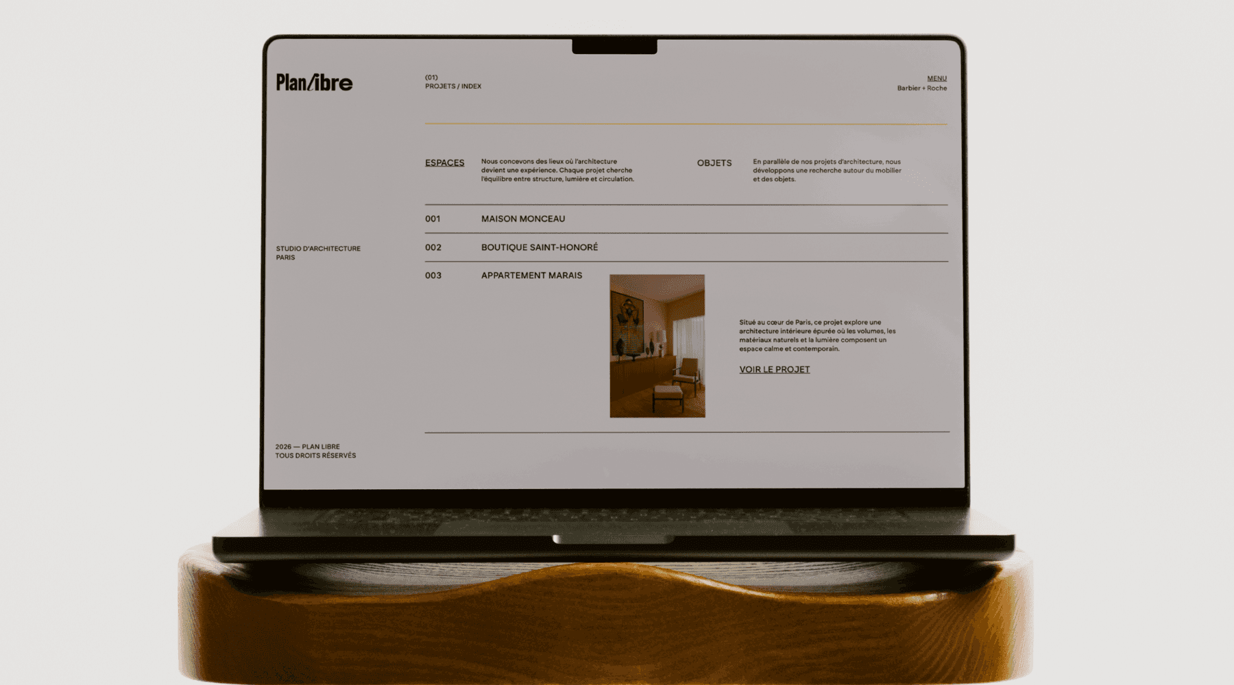 A young man in a white shirt and tie sits on the floor, surrounded by scattered papers. He looks down at a document, appearing focused and pensive.