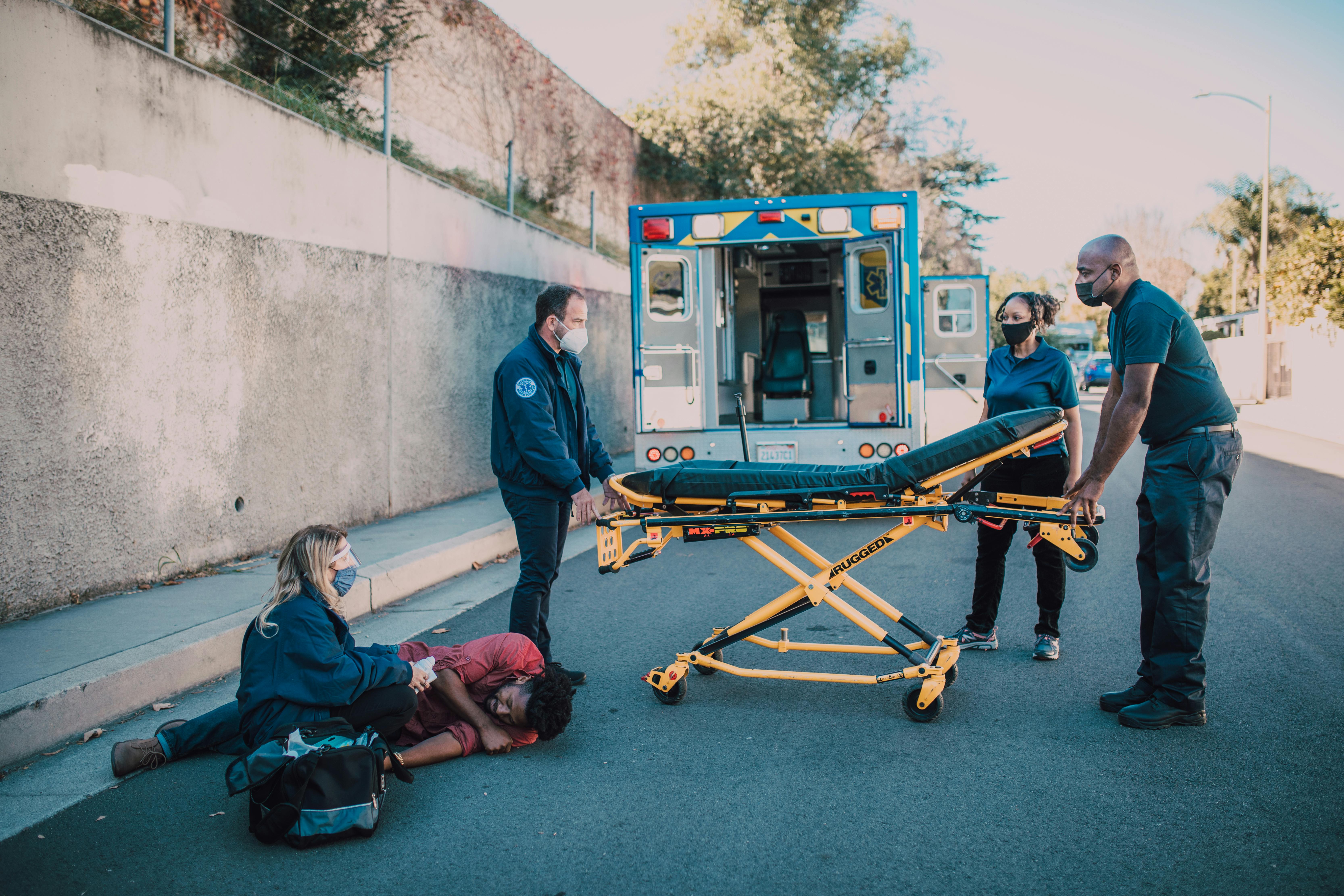 A picture of EMT team responding to emergency with stretcher near open ambulance