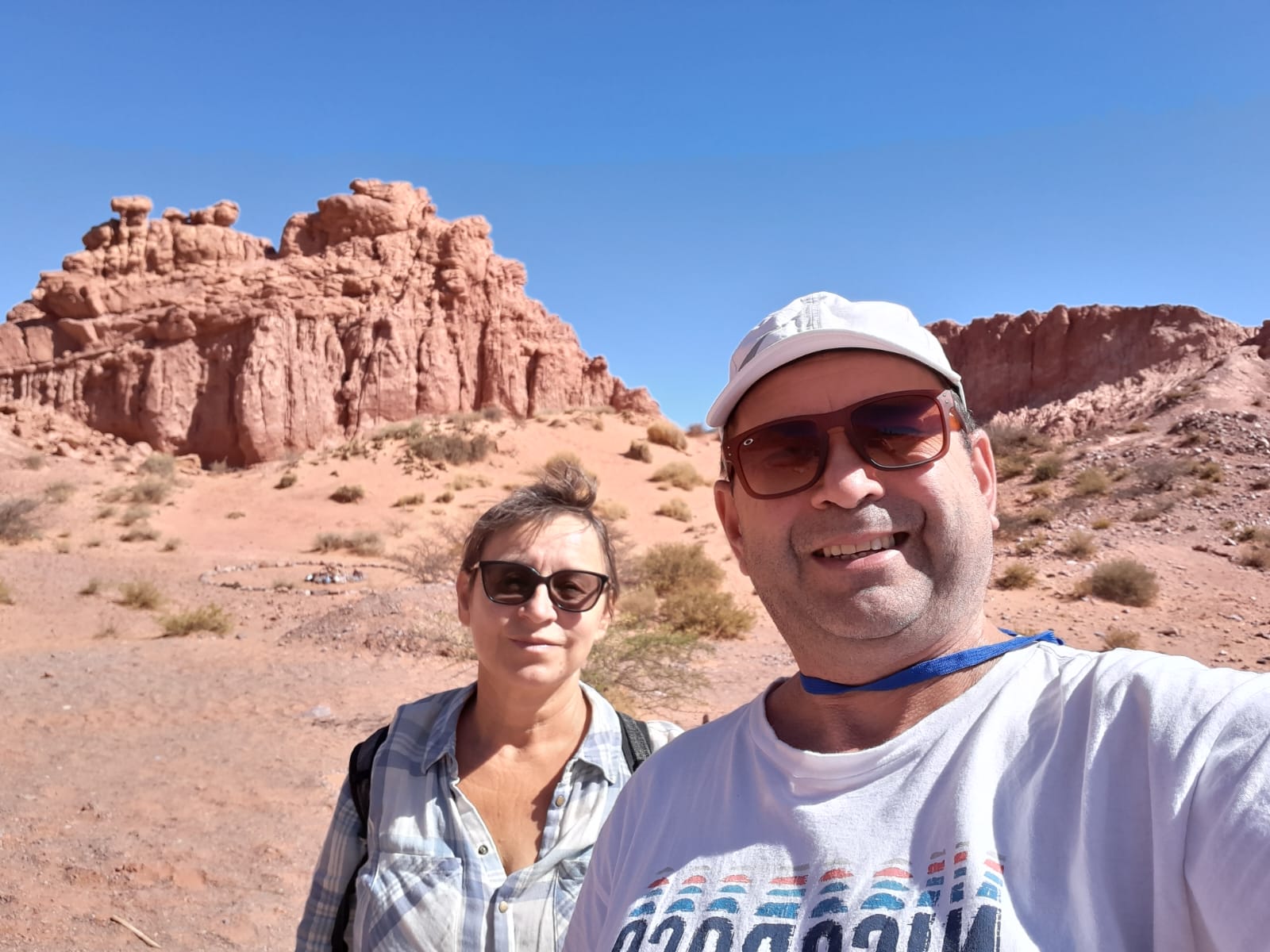 Mujer sentada sobre un tronco frente a una cascada doble en un bosque frondoso de Argentina.