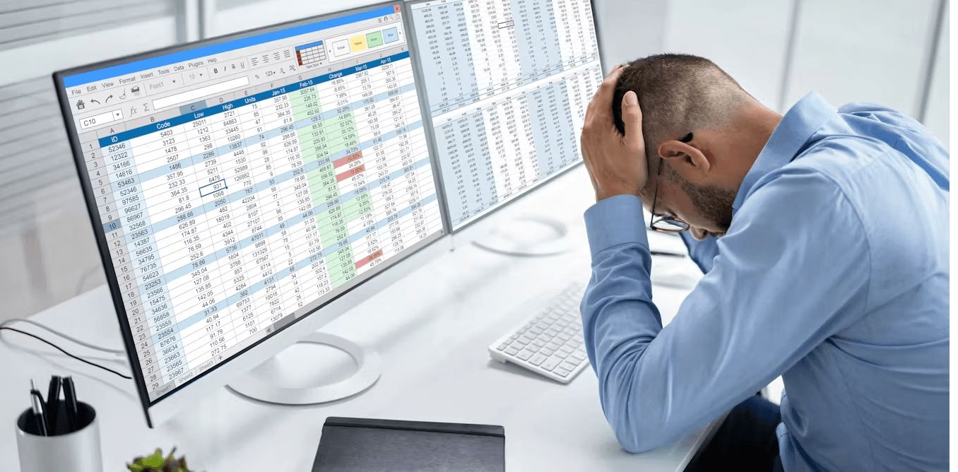 Stressed man looking at complex spreadsheets - How to Automate Excel Reports