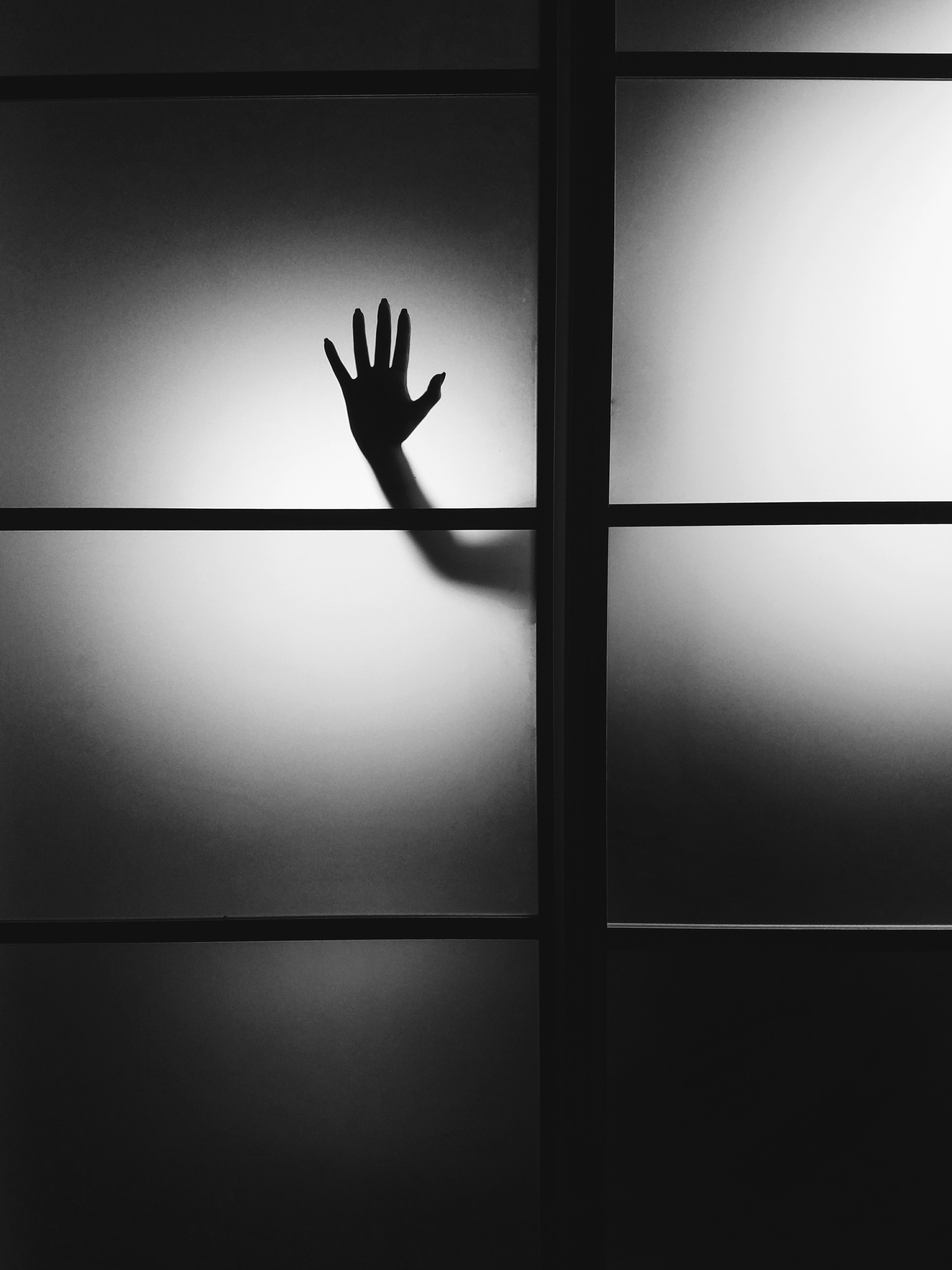 Black and white minimalist photo of a hand behind a wall