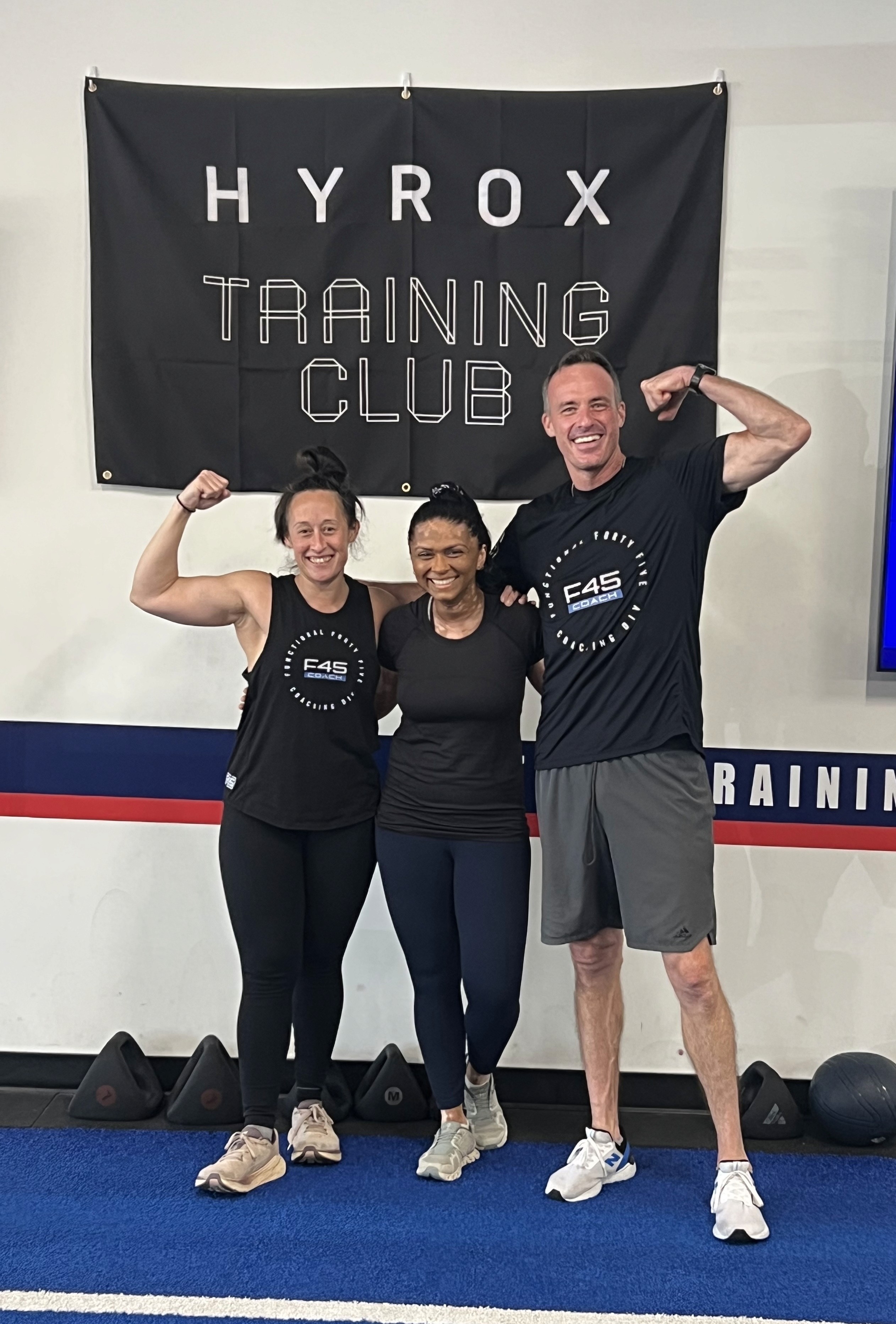 Sanji with her coaches beneath a HYROX Training Club banner.