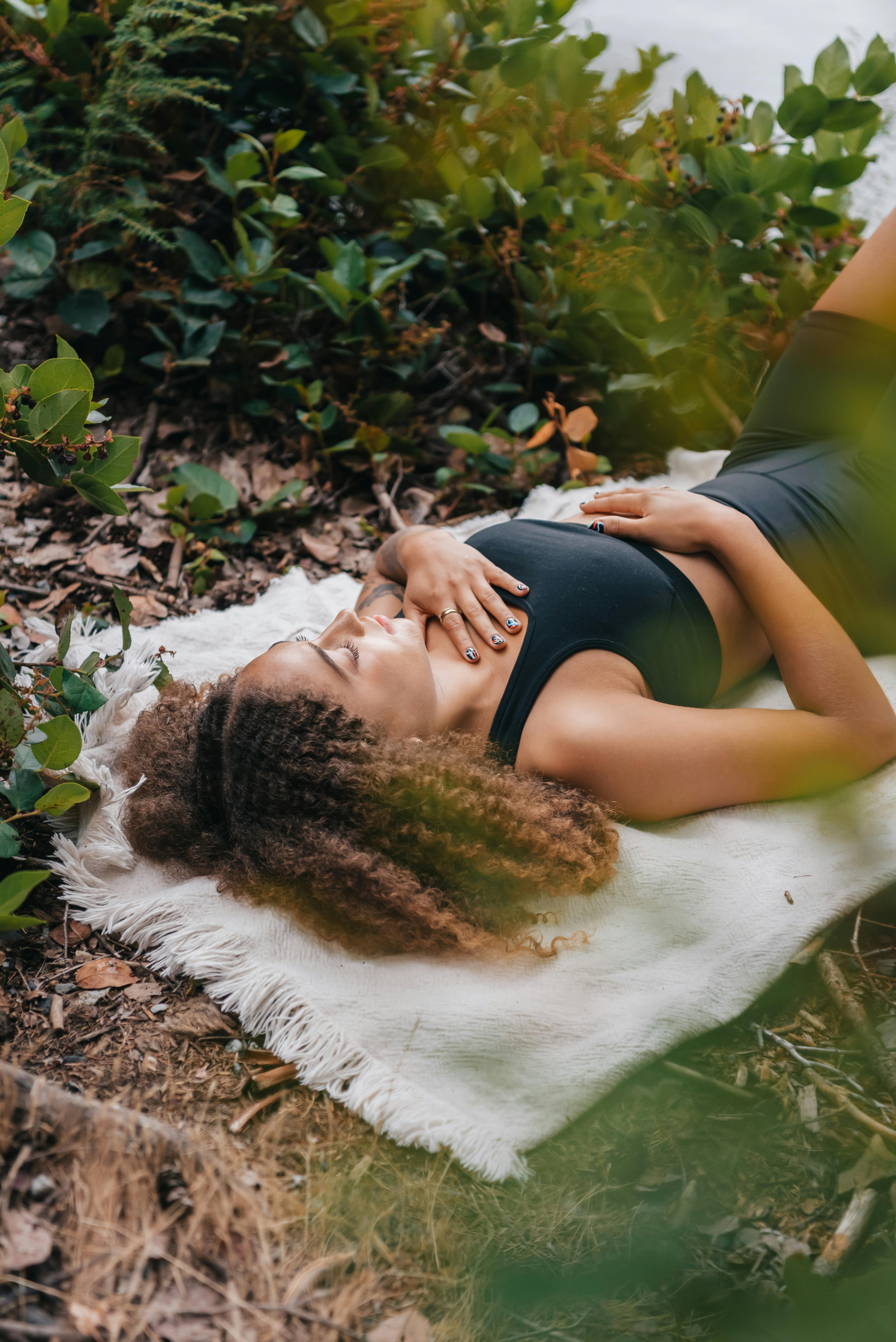 woman laying down with her hand on her chest and the other heand on her belly