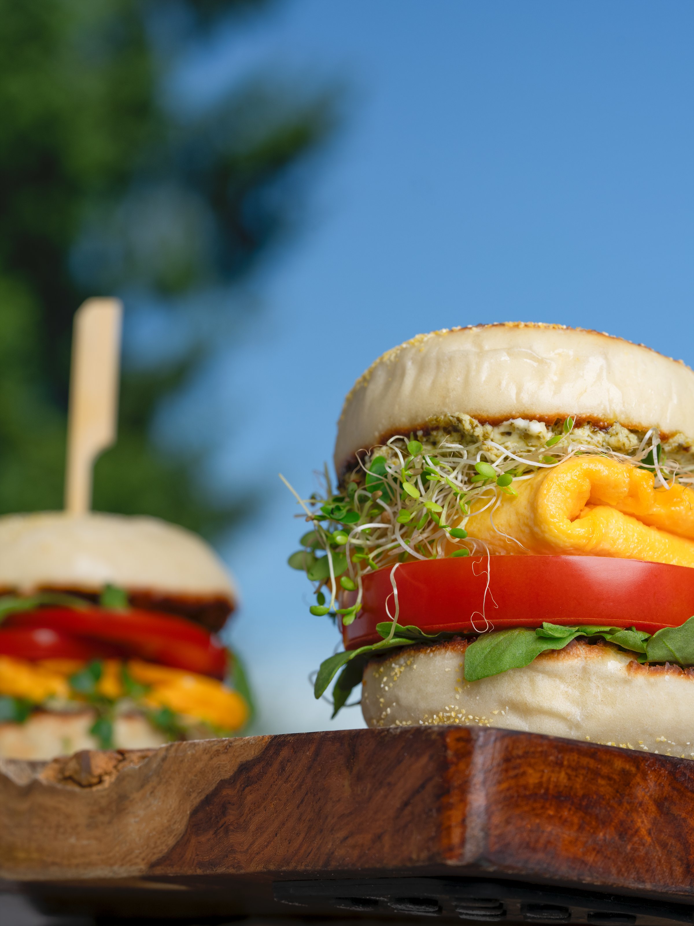 Commercial food styling featuring stacked vegetable burgers with fresh ingredients and shallow depth of field.