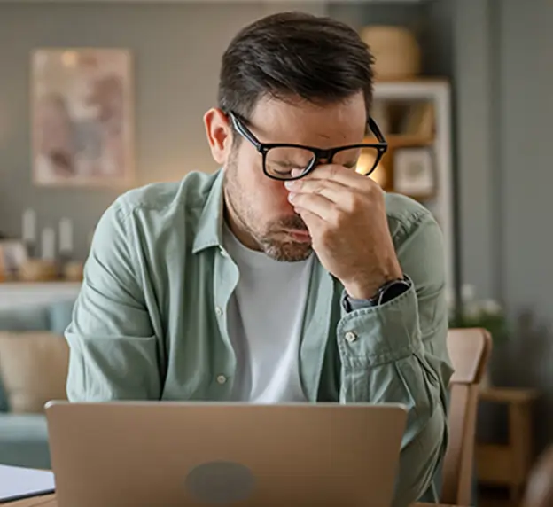 Man at desk struggling with headache.