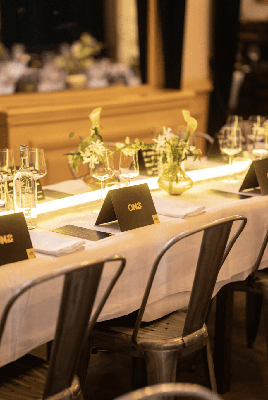 A smiling young man with crossed arms, wearing a plaid shirt and white t-shirt, poses against a dark background.