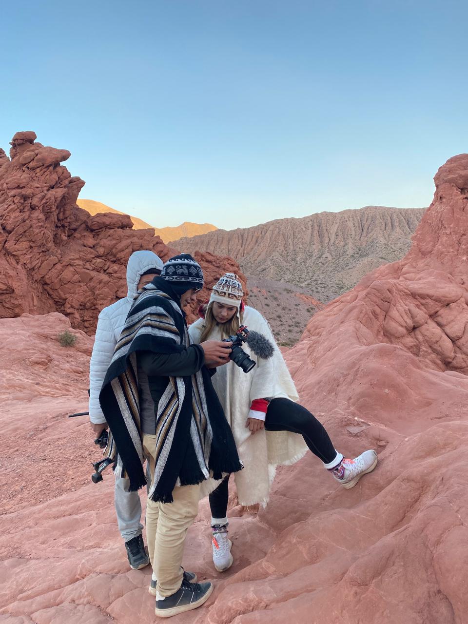 Mujer sentada sobre un tronco frente a una cascada doble en un bosque frondoso de Argentina.