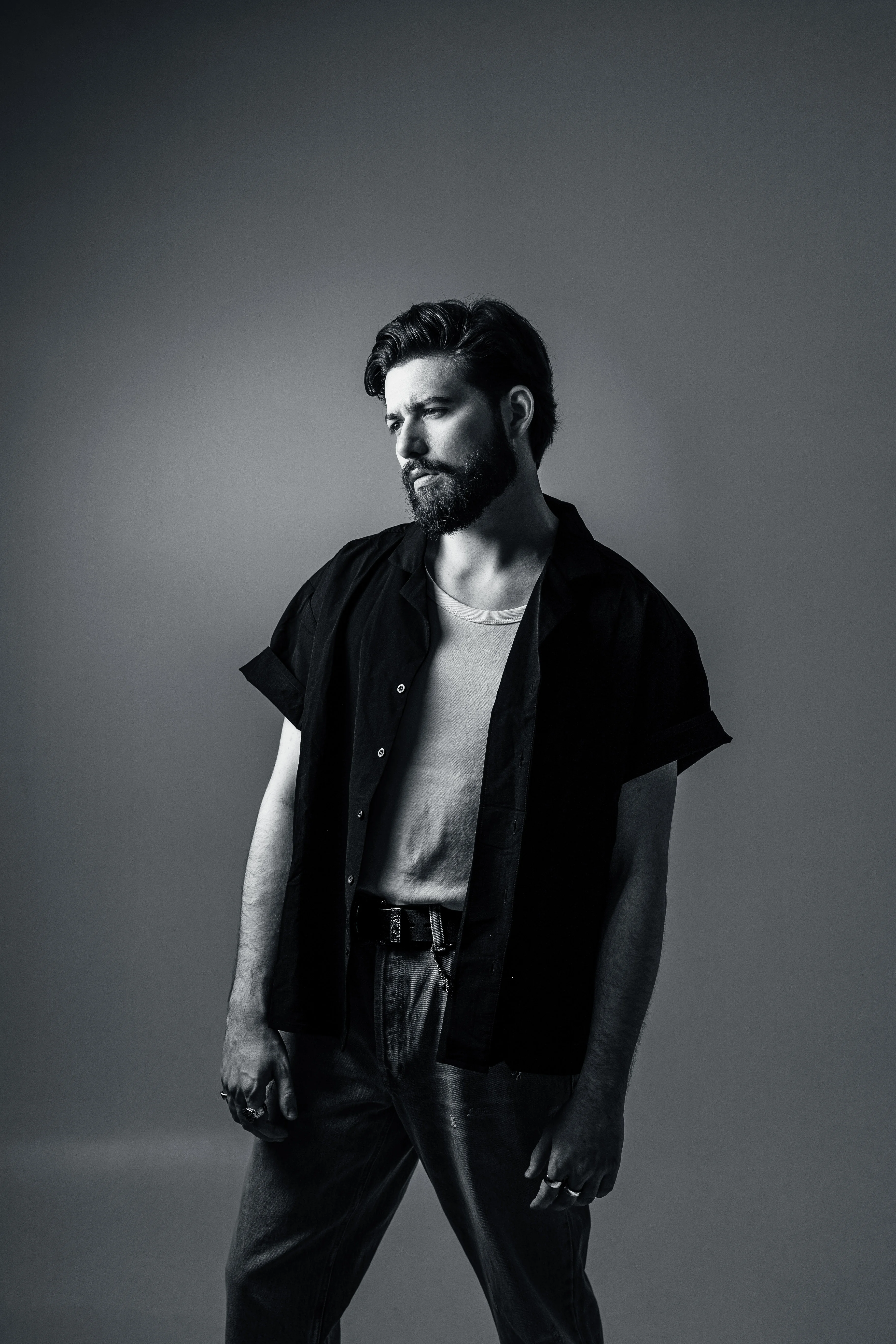 Férfi világos háttér előtt, pólóban és fekete ingben, komoly arckifejezéssel, fekete-fehér stílusban. Nordix Studió