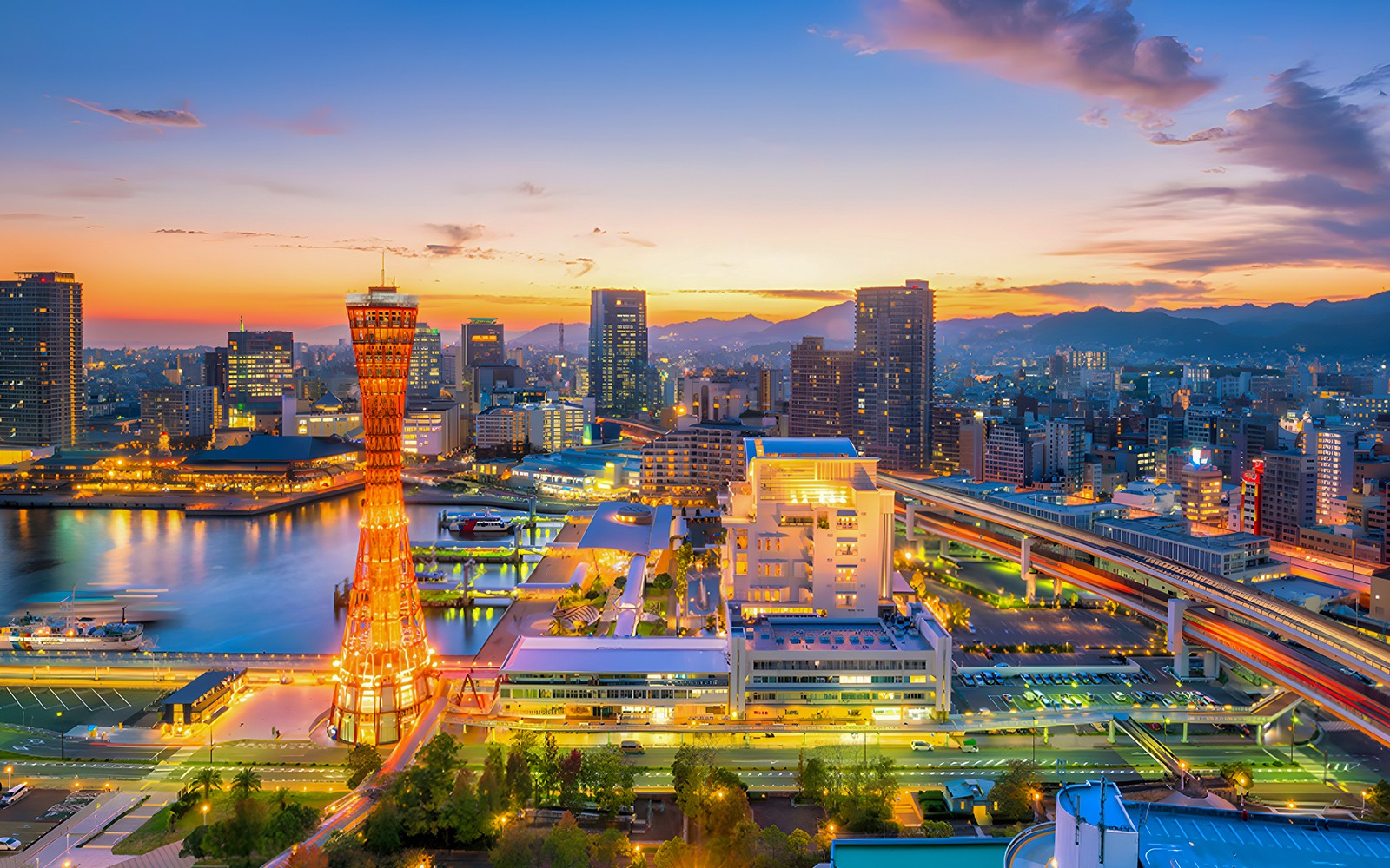 Kobe cityscape at sunset with illuminated Kobe Port Tower and skyline.