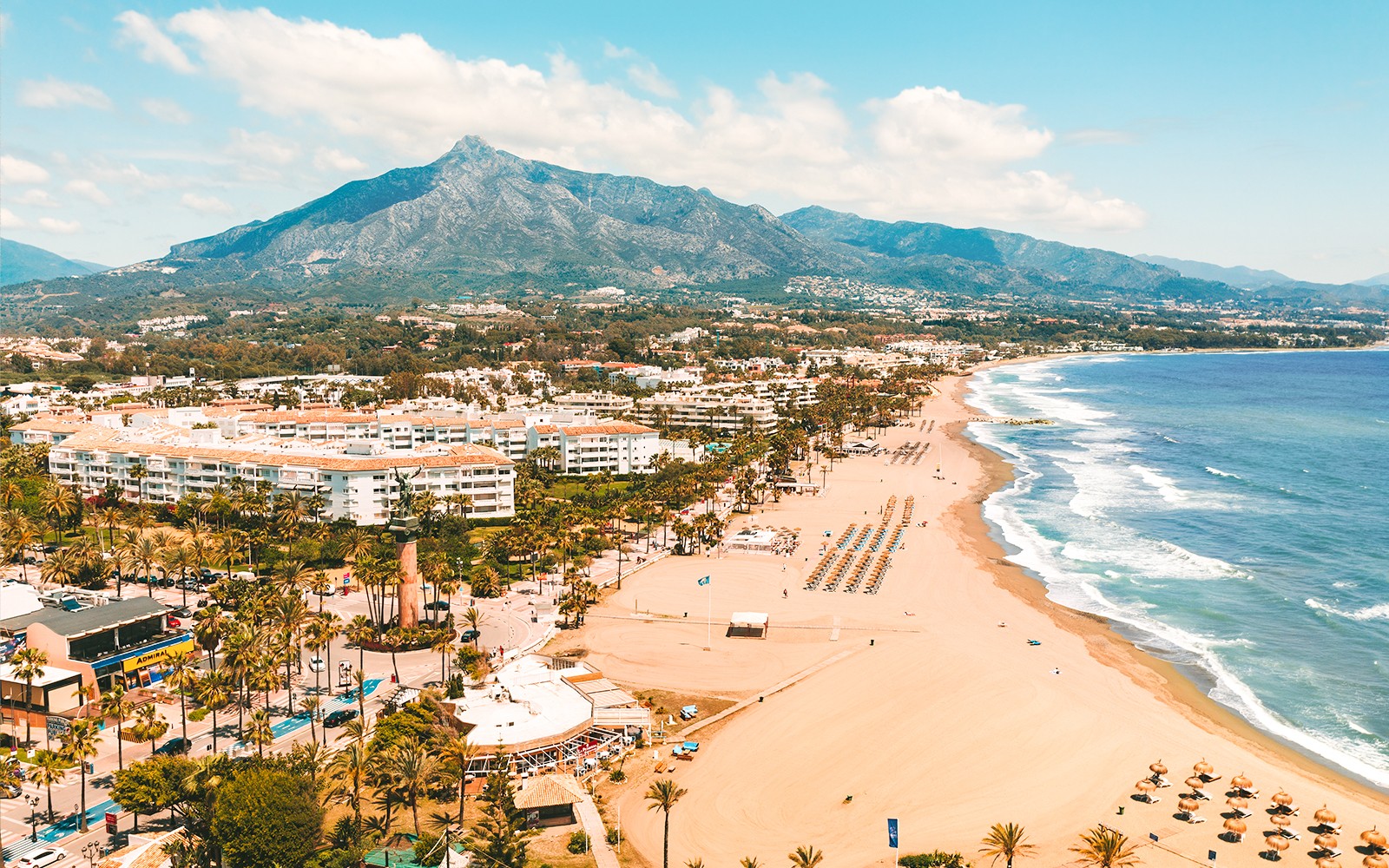 Aerial view of Marbella beach with mountains in the background, part of the Málaga tour.