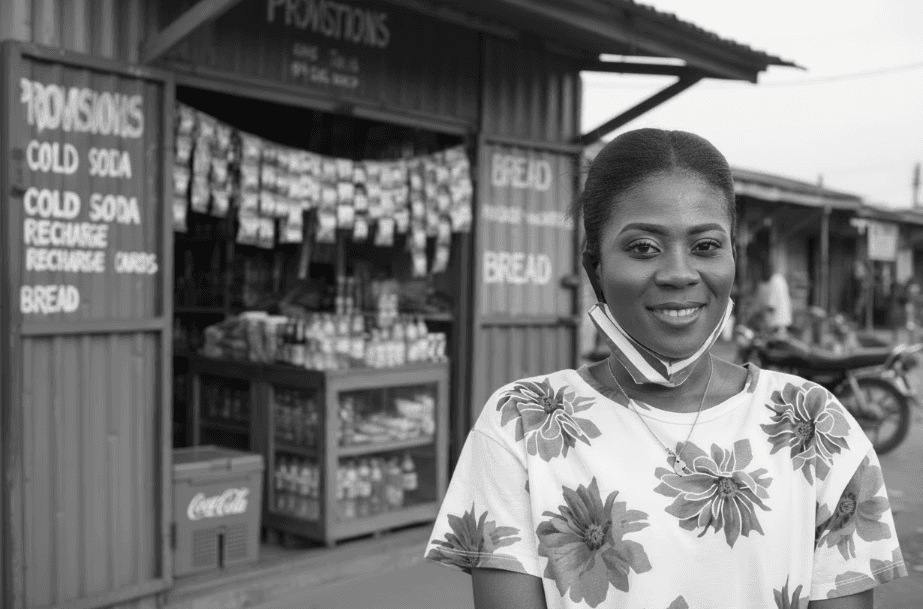 Smiling Nigerian woman in front of a local shop, symbolizing authenticity, verified identity, and community trust through Profiled Nigeria.