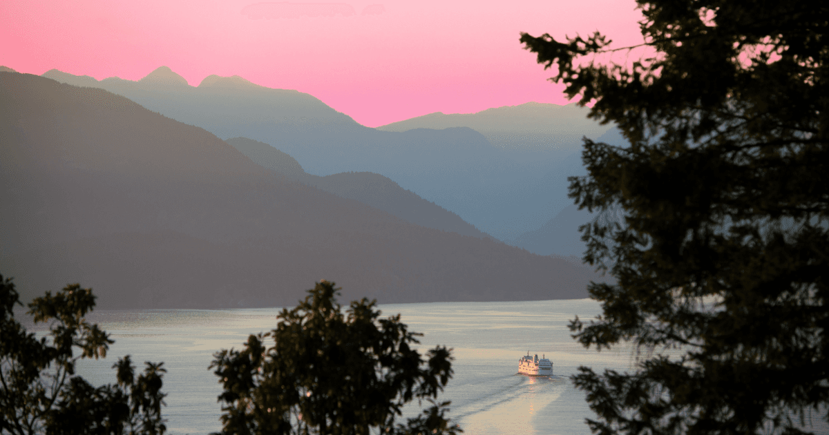 An outdoor landscape at sunset with trees, water, and a boat