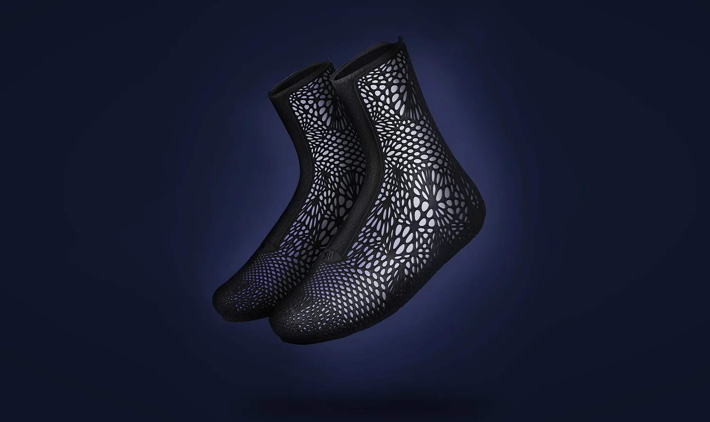 Pair of black lattice SOLS ADAPTIV footwear prototypes on a dark blue background
