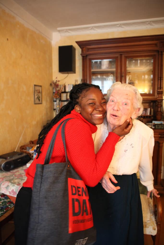 Une auxiliaire de vie souriante, joue contre joue avec une dame âgée dans son salon